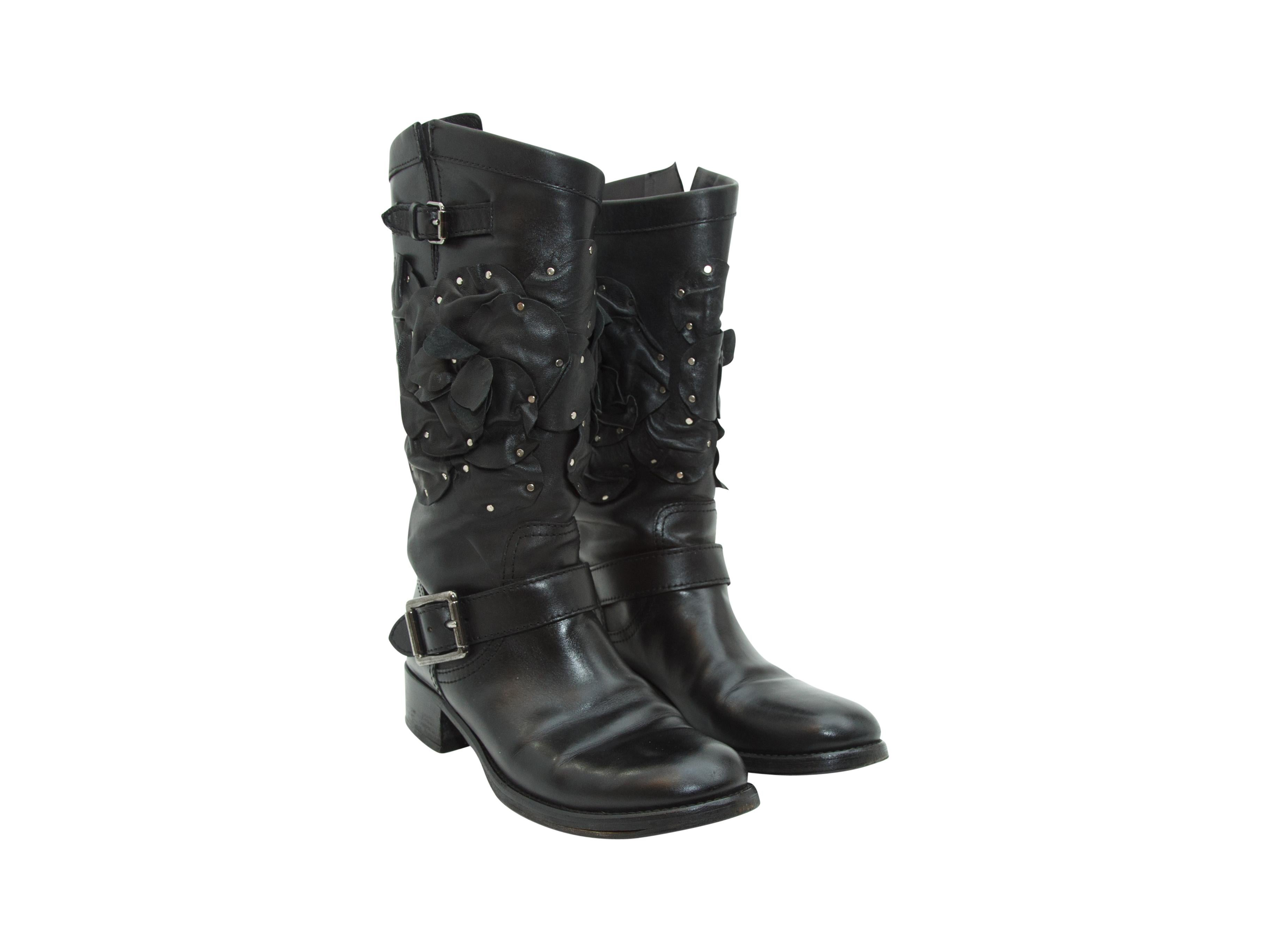 Product details:  Black tall leather boots by Valentino.  Accented with floral applique and flat studs.  Buckle strap accents.  Low stacked heel.  Round toe.  Pull-on style.  Antiqued silvertone hardware.  12.25