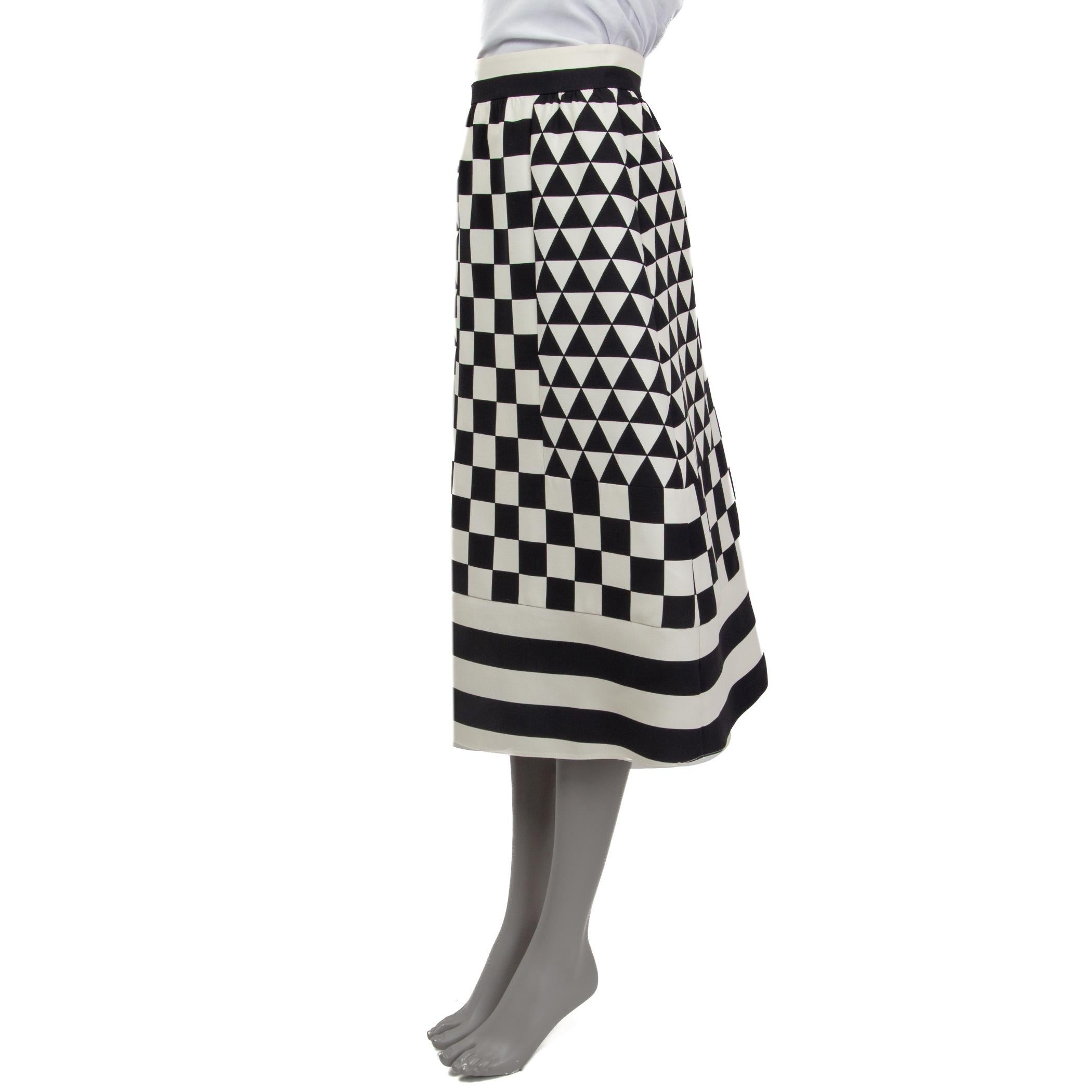 100% authentic Valentino geometric checkerboard-print midi skirt in black and off-white virgin wool (65%) and silk (35%). Features two slit pockets on the side. Opens with concealed zipper and a hook at the back. Lined in off-white silk (100%). Has