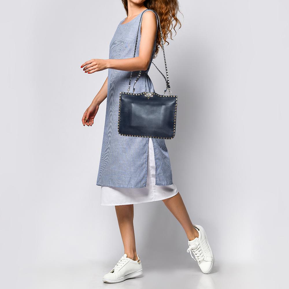 Valentino brings you this super-stylish tote that carries a design that transcends trends. It has a blue leather exterior decorated with the signature pyramid Rockstuds. The tote is complete with a spacious fabric interior, two top handles, and a