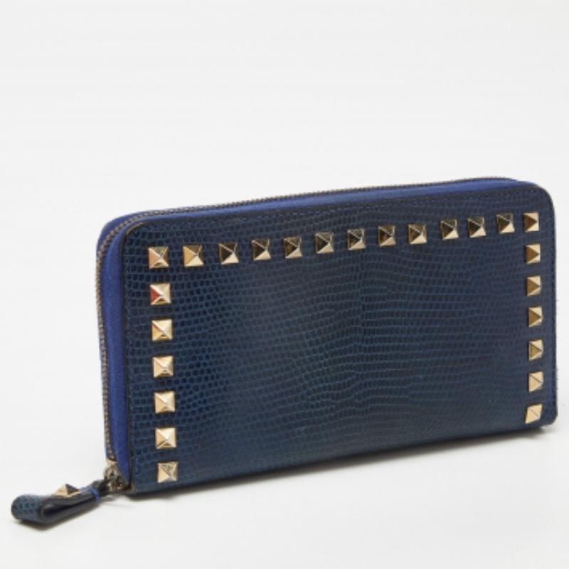 Les Rockstuds soulignent joliment l'extérieur bleu de ce portefeuille Valentino. Réalisé en peau de lézard, il présente la signature de la marque au dos, un intérieur doublé avec différentes fentes et une fermeture à glissière.