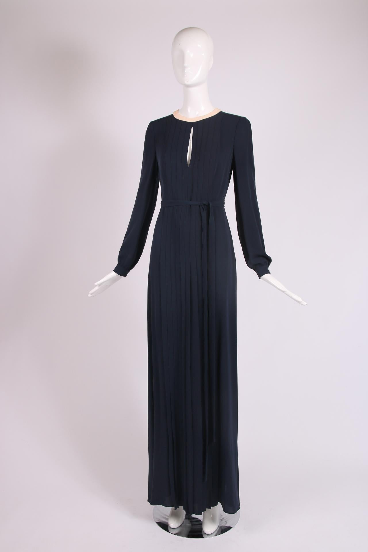 Valentino navy silk gown with blush pink trim at the neckline and with a keyhole opening, pleated skirt, self belt and open back. Size 40, 100% silk. In excellent condition. Please consult measurements.

Shoulders - 14