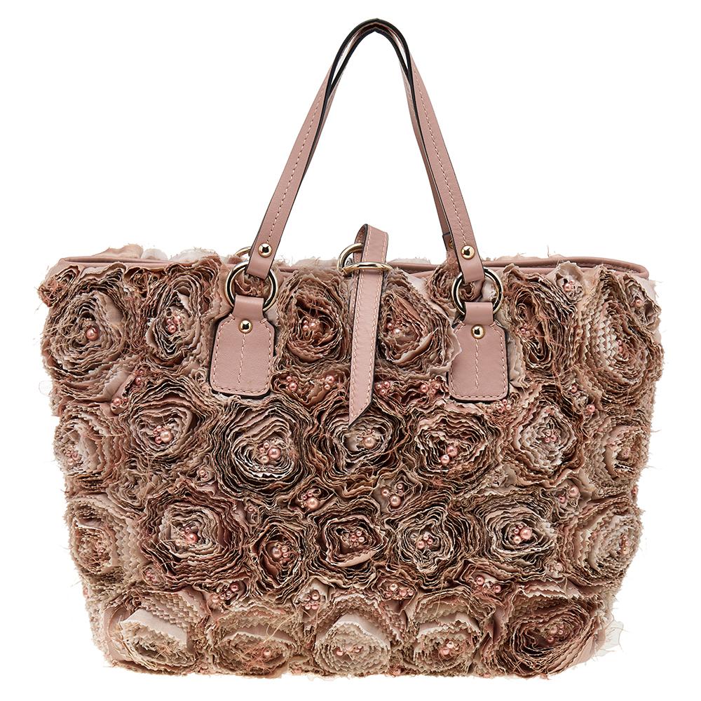 Set in a dreamy design and style, this Rosier tote from the House of Valentino is absolutely mesmerizing! This lovely tote features blush pink organza applique and leather trims all over the exterior. It has gold-toned fittings, a fabric-leather