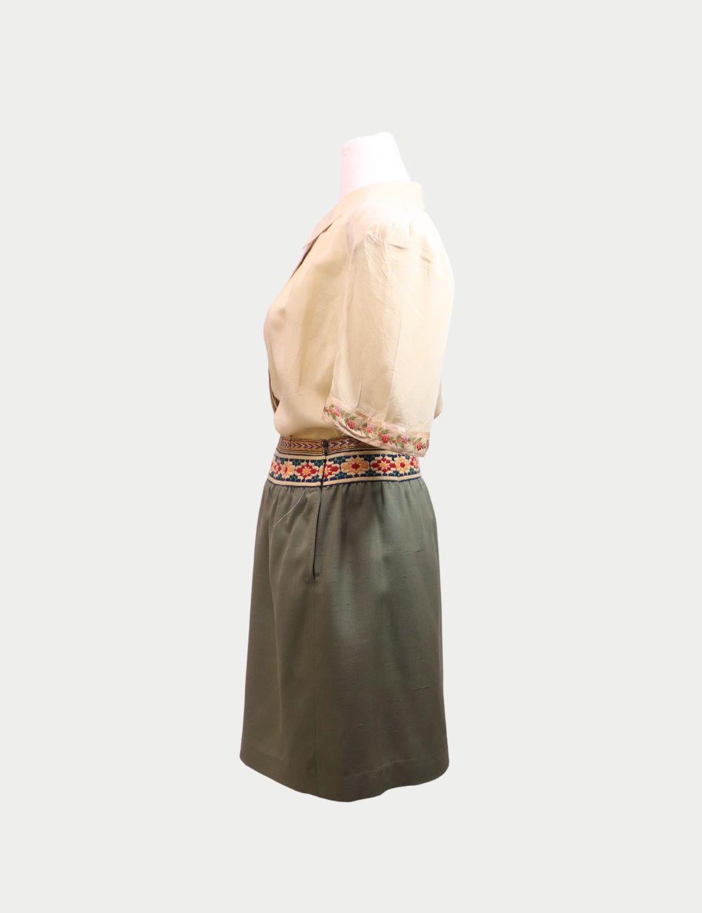 Step into timeless elegance with this Valentino Boutique Vintage Two-Piece Set, featuring a chic sage-green skirt and a cream blouse with delicate embroidery. The skirt is tailored in a classic straight silhouette, adorned with a vibrant floral