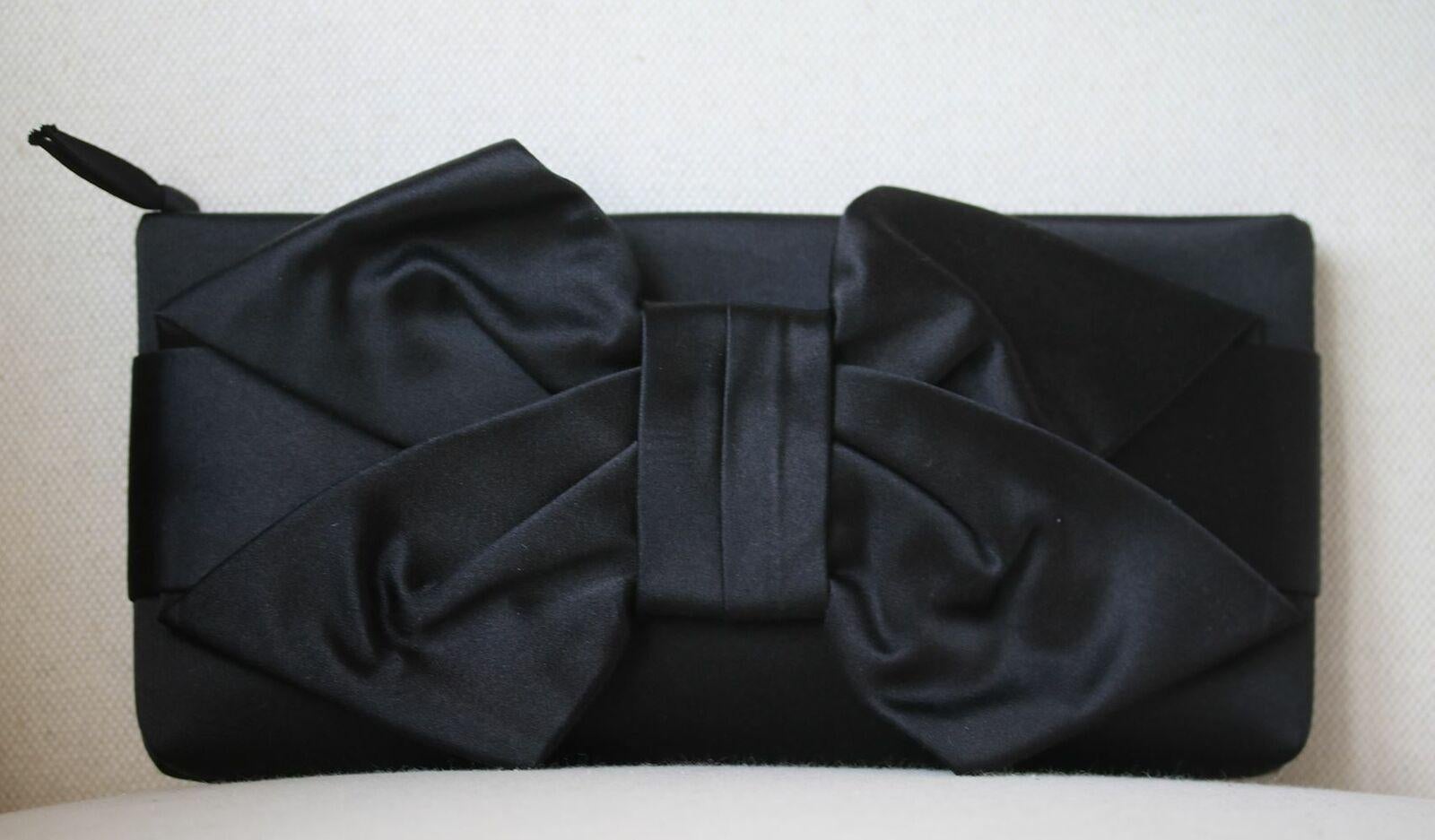 Bedecked with a beautiful bow, Valentino's black silk-satin clutch is an elegantly feminine accessory. Black silk-satin. Bow detail. Internal pouch pocket. Fully lined in champagne satin. Zip fastening along top.

Dimensions: D 2 cm x H 13 cm x W 27