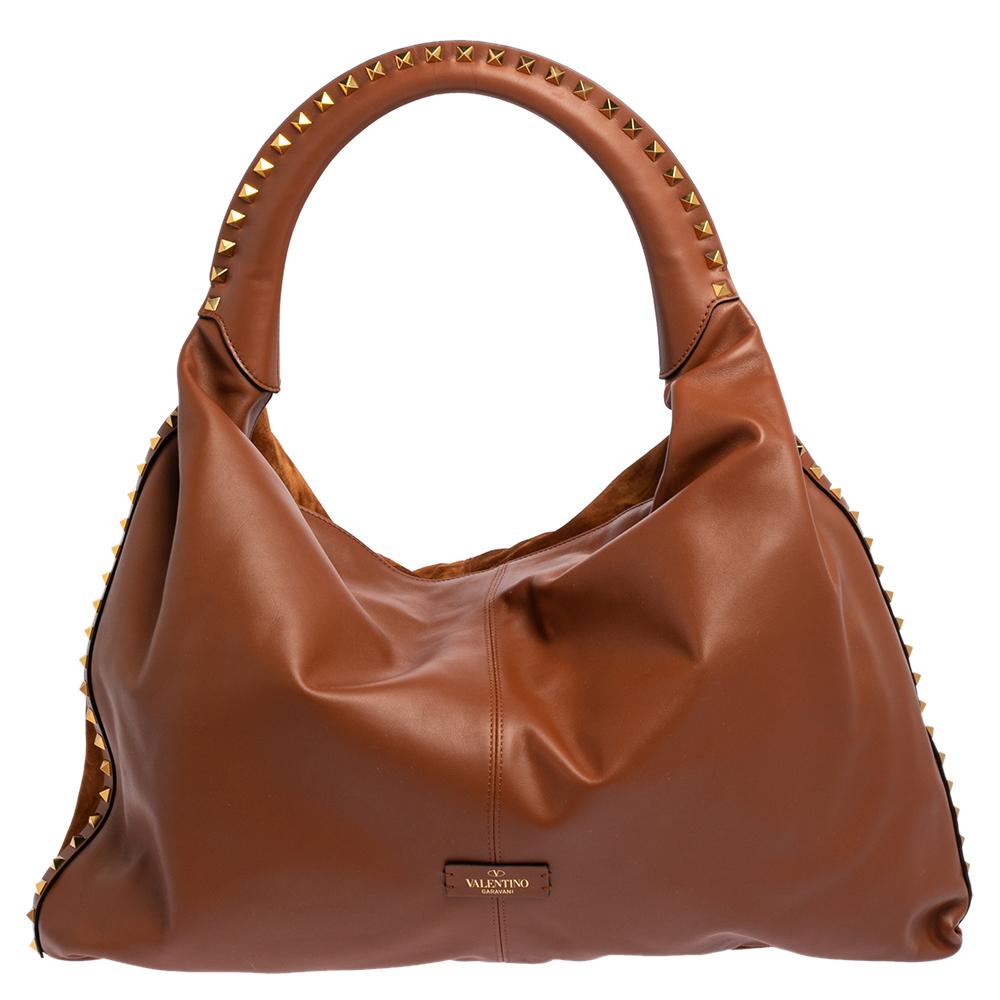 Valentino handbags are known for their unique designs that emanate the label's feminine verve and immaculate craftsmanship that makes their creations last season after season. Crafted from suede and leather in a versatile brown shade, the exterior