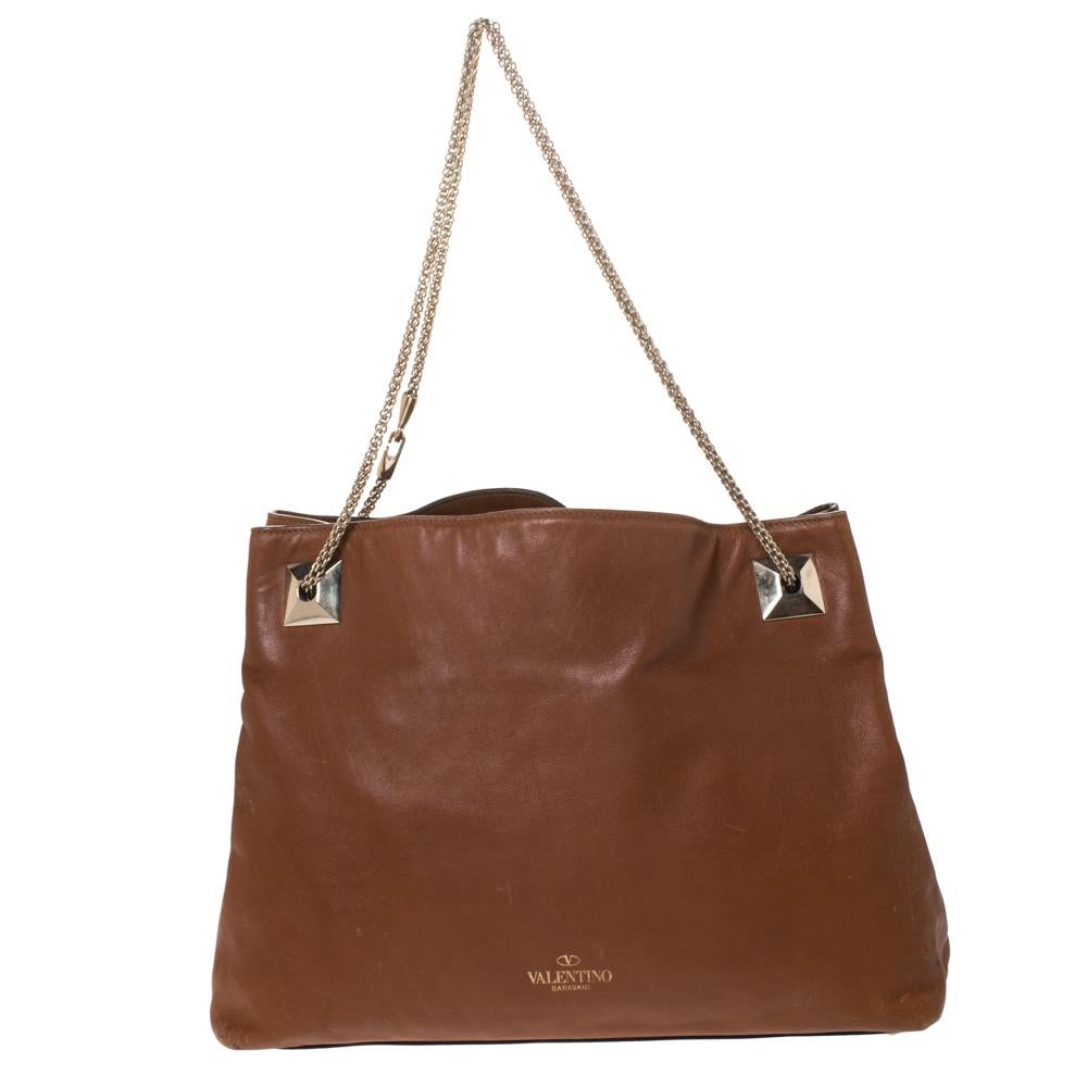 This Valentino tote is a must-have in your wardrobe. Smoothly glide from day to night with the help of this versatile leather bag that has a superior design. It comes in brown and is equipped with chain handles and a spacious fabric-lined