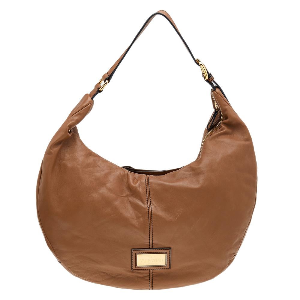 Offering a blend of luxe elegance and everyday essentiality, this hobo designed by Valentino ensures that your handbag needs are taken care of. It is made from brown leather with a Rose Petale motif on the front. The back is adorned with a
