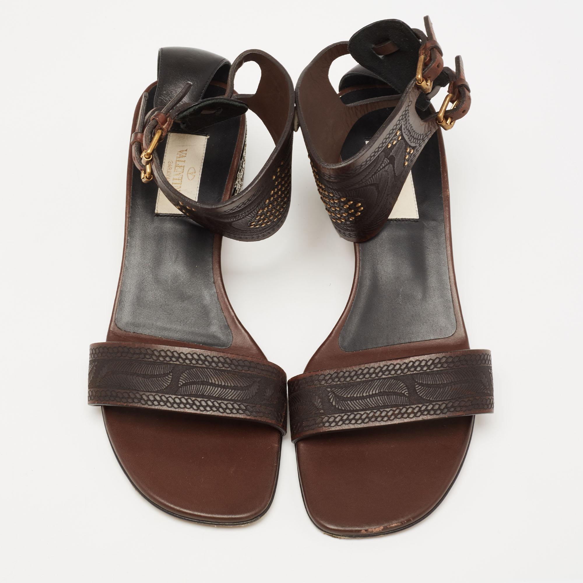 These sandals from the House of Valentino are all about class and elegance! They are made from brown leather, which is highlighted with studded embellishments. They display gold-tone hardware, block heels, and an ankle strap. Flaunt your chic style