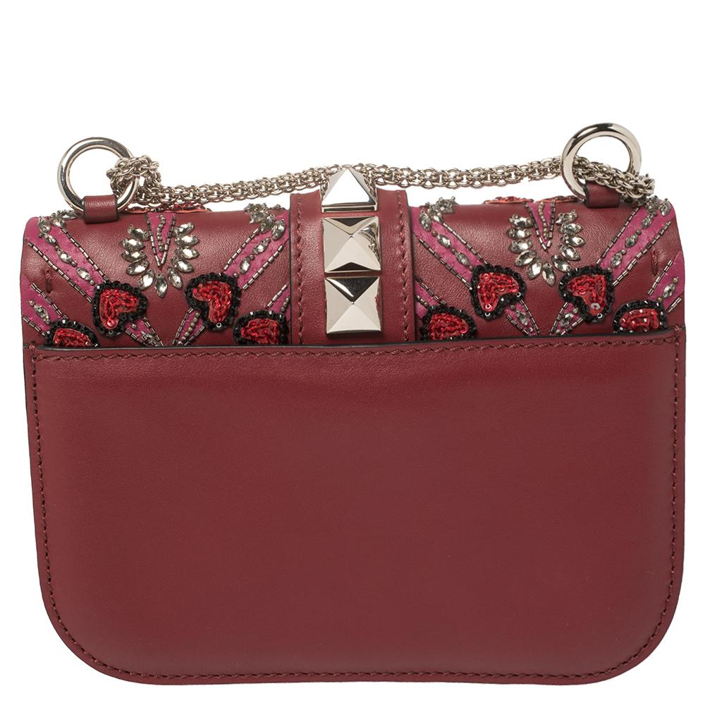 Valentino’s famed Glam Lock bag is taken to glamorous new heights. This burgundy leather style comes adorned with a 'Love Blade' design featuring heart motifs, bead, and crystal embellishments throughout the front and finished with signature