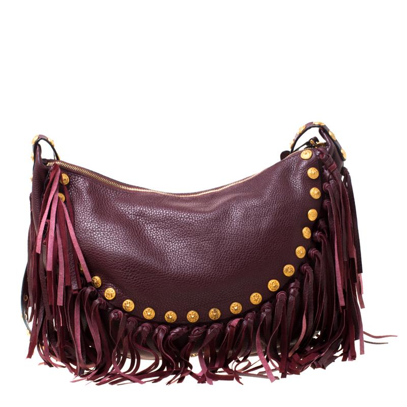Chic and posh, this Valentino hobo is sure to enchant onlookers. The burgundy beauty is crafted from leather and features edgy fringes and gold-tone stud details on its exterior. It flaunts a single adjustable strap and the top zipper opens to a