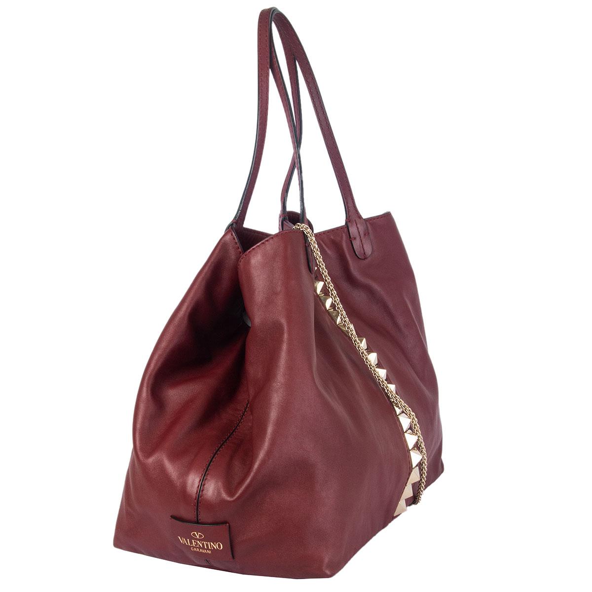 100% authentic Valentino Large Va Va Voom tote bag in burgundy smooth leather featuring light gold-tone signature pyramid studs. Closes with a buckle and is lined in beige canvas with one zipper pocket against the back and two open pockets against