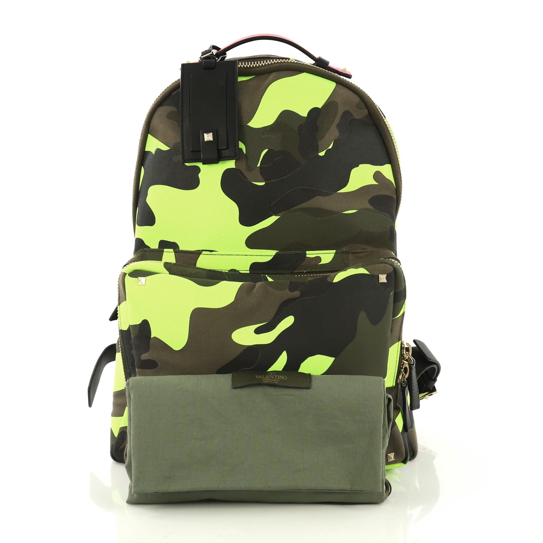 This Valentino Camouflage Backpack Nylon and Leather Large, crafted in green Multicolor Camouflage Nylon and Leather, features dual shoulder straps, stud detailing, exterior front zip pocket and aged gold-tone hardare. Its zip closure opens to a