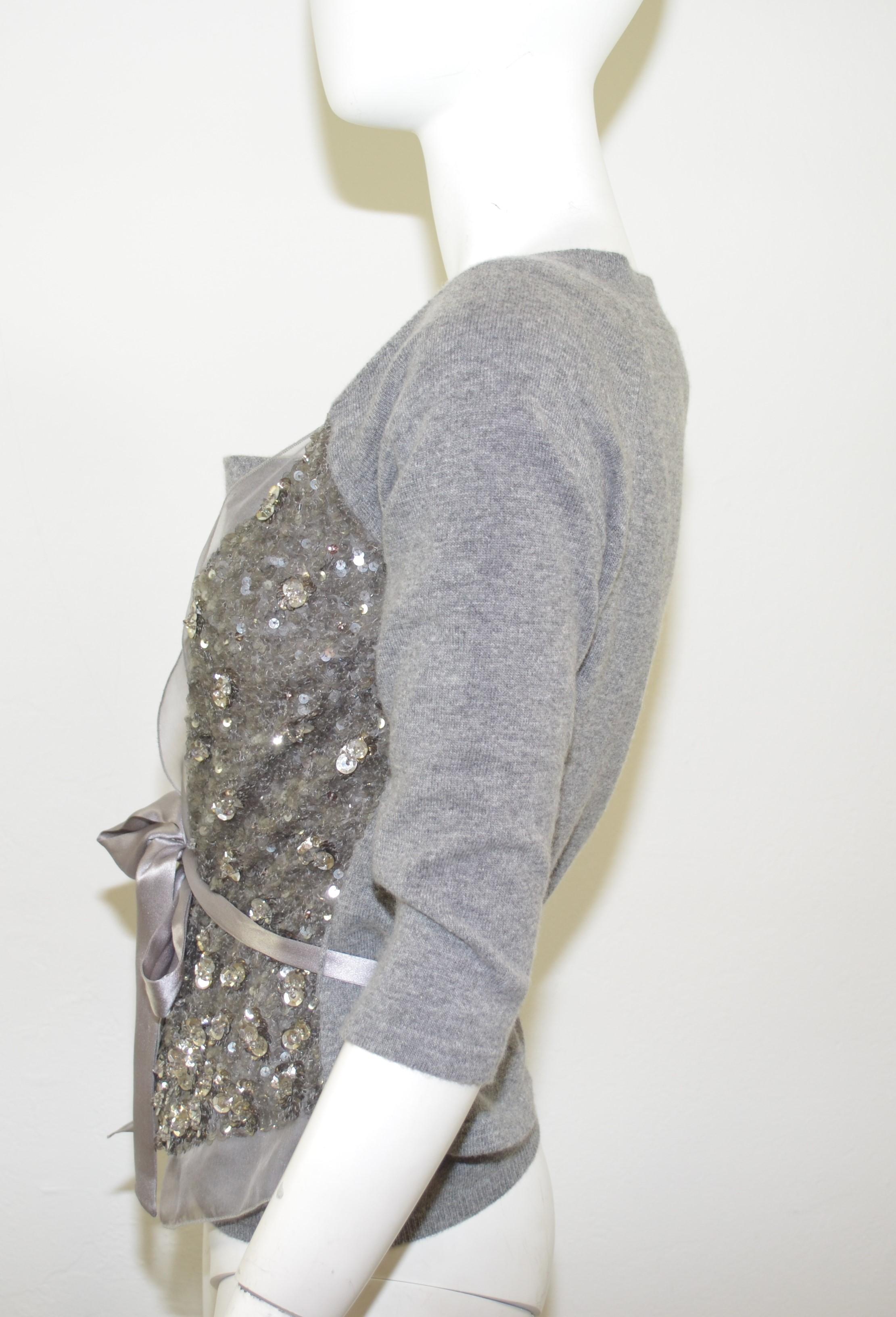 Valentino grey knit cardigan sweater and shell top set feature silver sequin and bead embellishment with a sheer trimming at the front, sweater has a satin self-tie closure at the waist. Shell top has a cowl neckline. 70% wool, 30% cashmere with