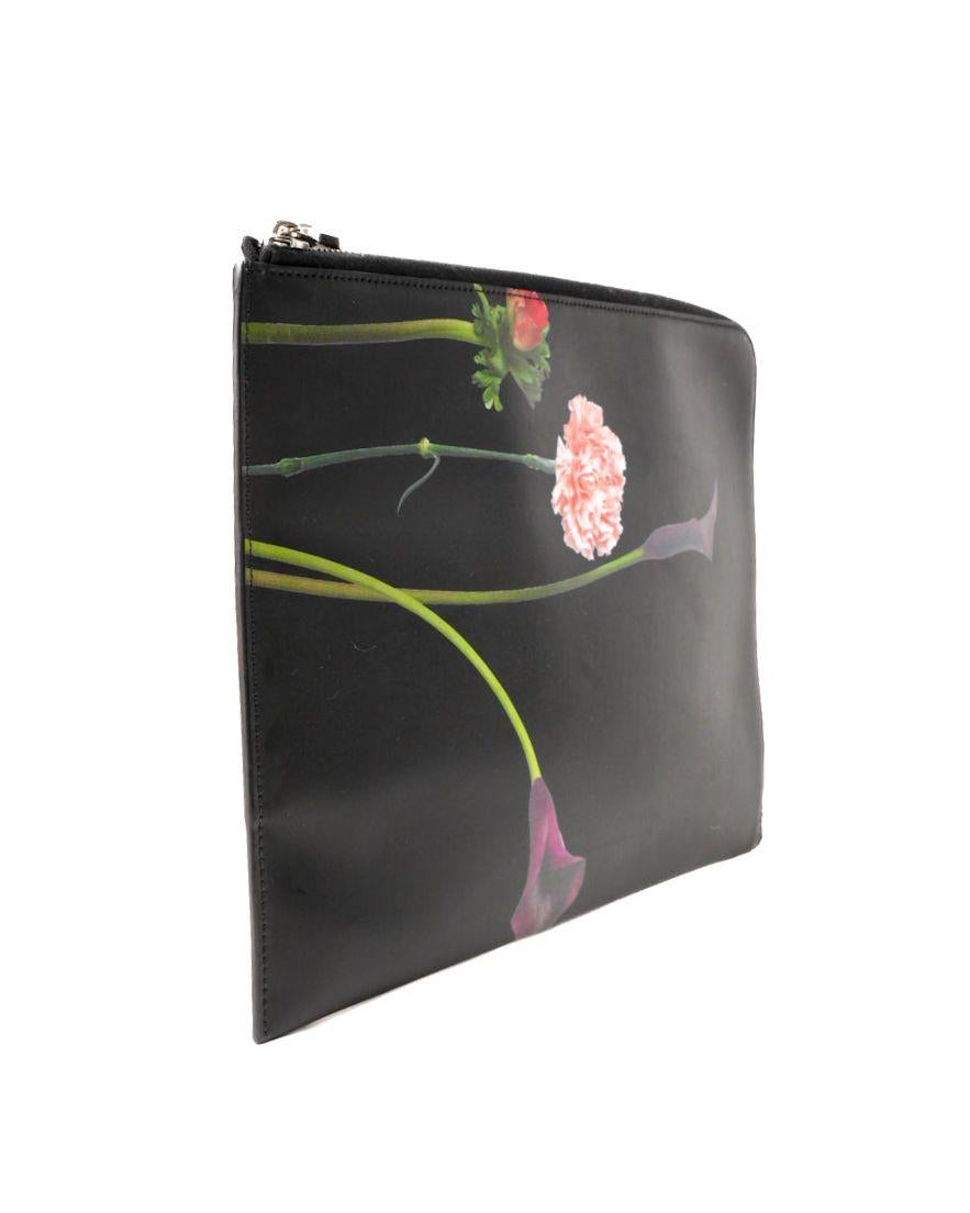 Clutch firmata Valentino, misura MM, realizzata in pelle liscia nera con una delicata stampa Peony sulla parte frontale e dettagli in hardware argentato. La chiusura semicircolare a zip offre sicurezza, mentre l’interno, rivestita in pelle liscia