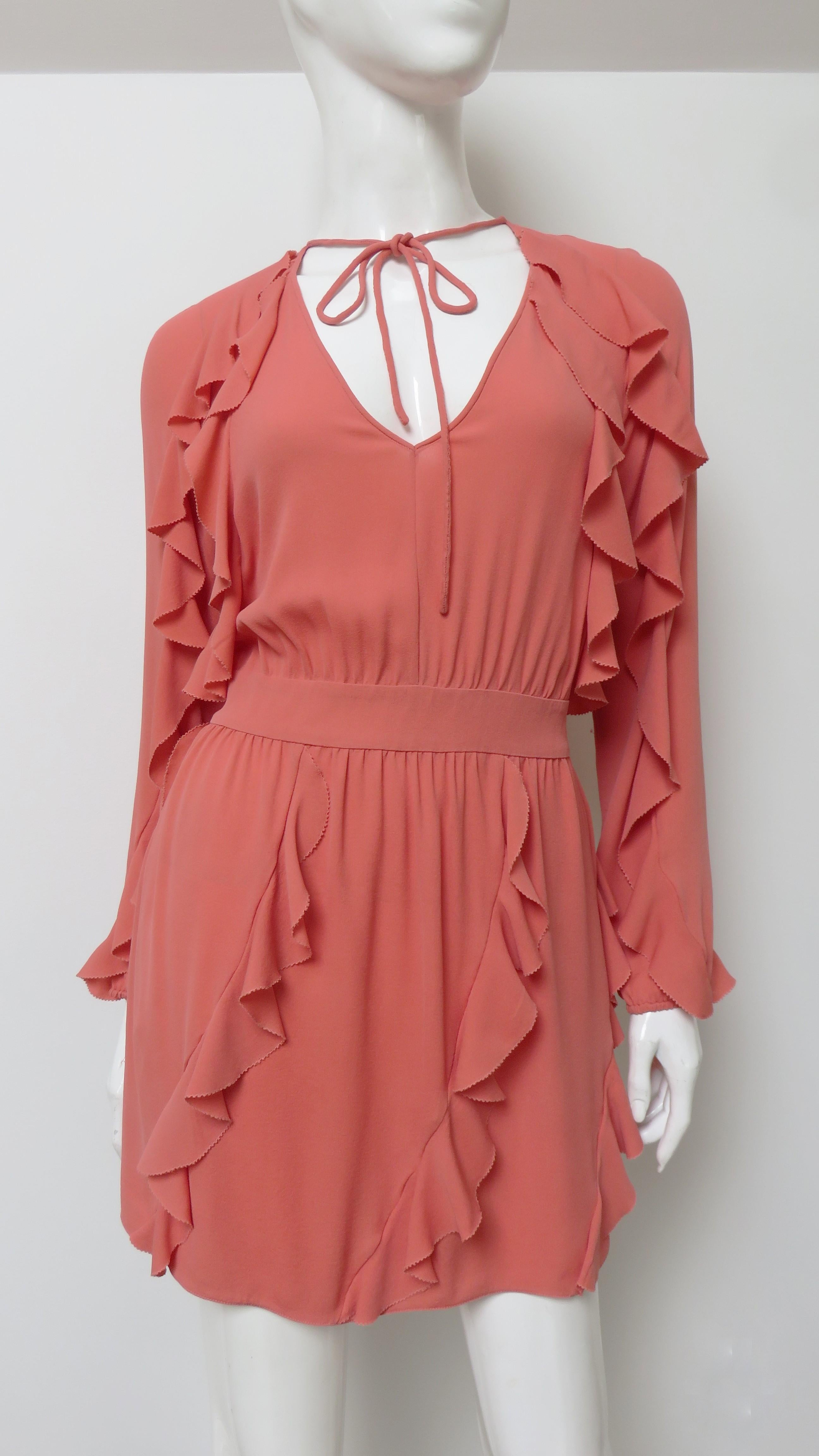 A gorgeous coral colored silk dress from Valentino.  It has a V neckline with an optional tie at the neck and long sleeves that gather at the wrists.  A band separates the bodice from the skirt portion which in addition to the sleeves have vertical