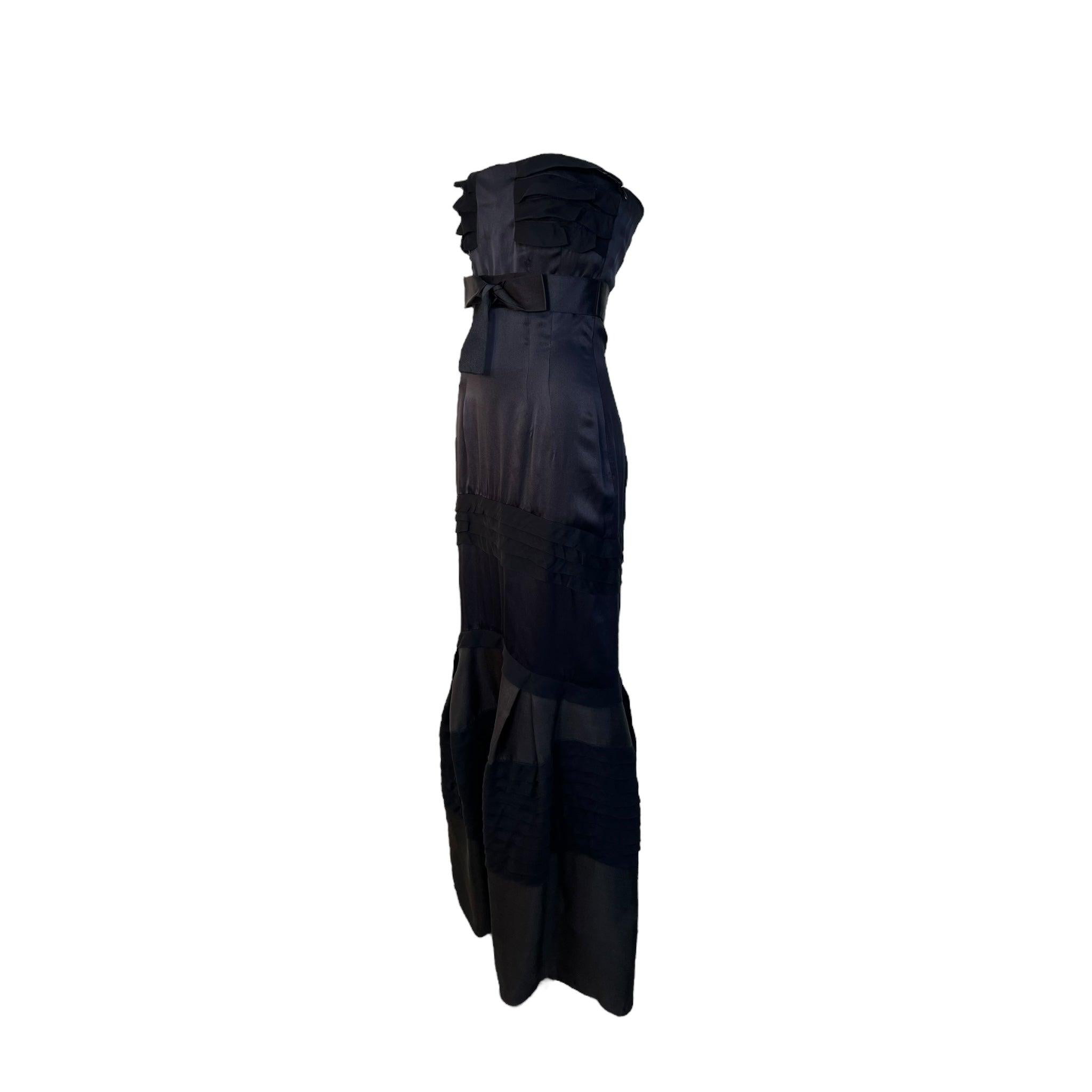 Dulce y sensual vestido de Valentino de su colección Invierno 2008. Cuerpo de charmeuse de seda negra y falda de organza. Volantes de pliegues de gasa de seda negra adornan el corpiño, las caderas y la falda. Lazo de cinta de raso negro bajo el