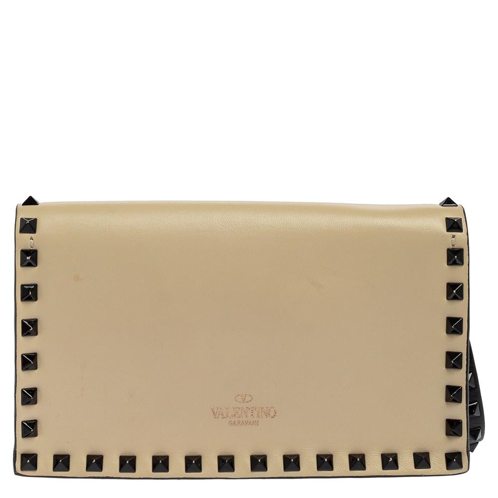The clutch to buy today is this one by Valentino! Crafted with expertise, the creation has shades of cream and black on the leather exterior, two leather compartments, and signature studs in black-tone forming a fine outline. The clutch can be