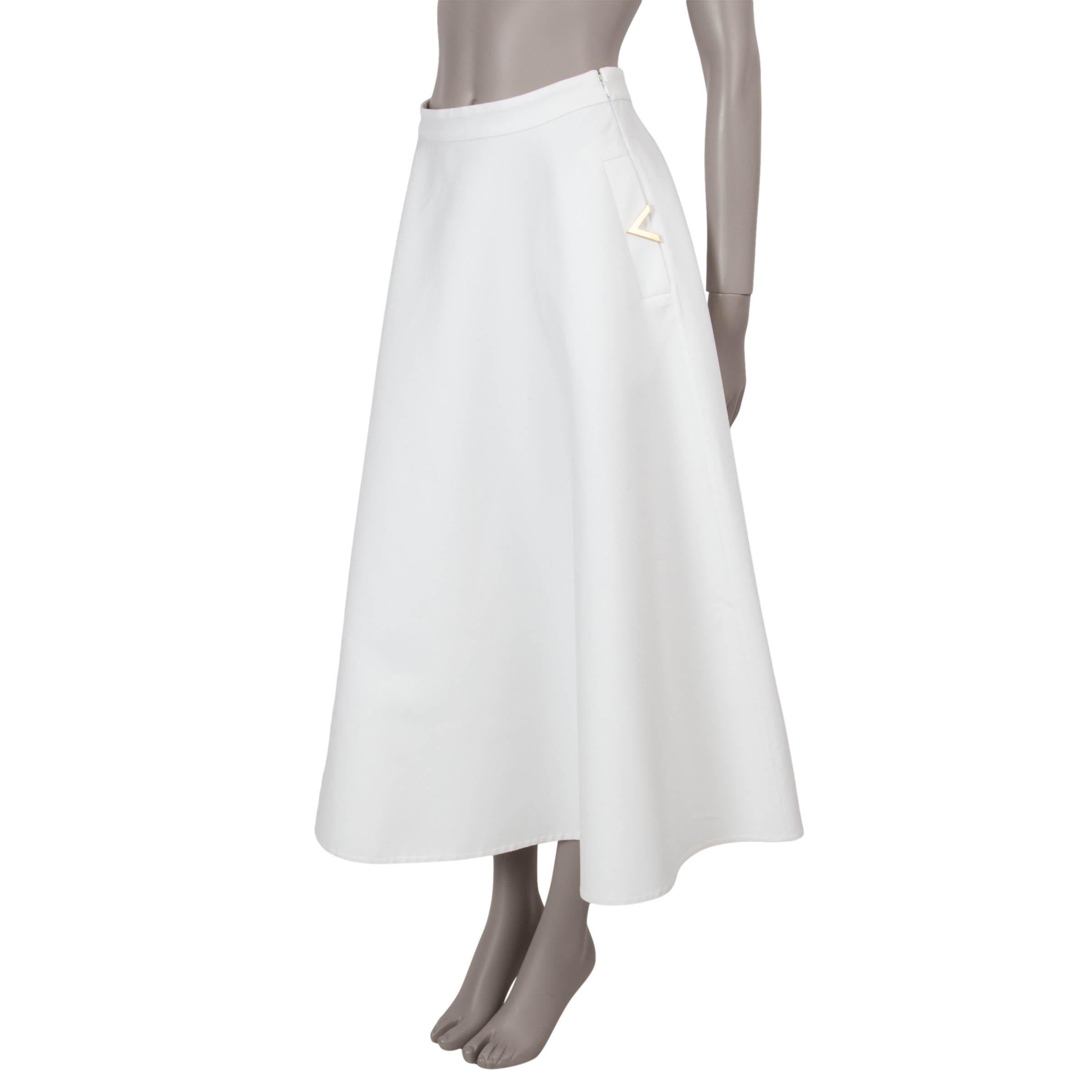 Cette jupe en crêpe Couture 100% authentique de Valentino, en laine crème (65%) et soie (35%), respire l'élégance intemporelle. Conçue avec une silhouette évasée et mi-longue, elle présente deux poches obliques ornées de détails VLogo dorés pour une