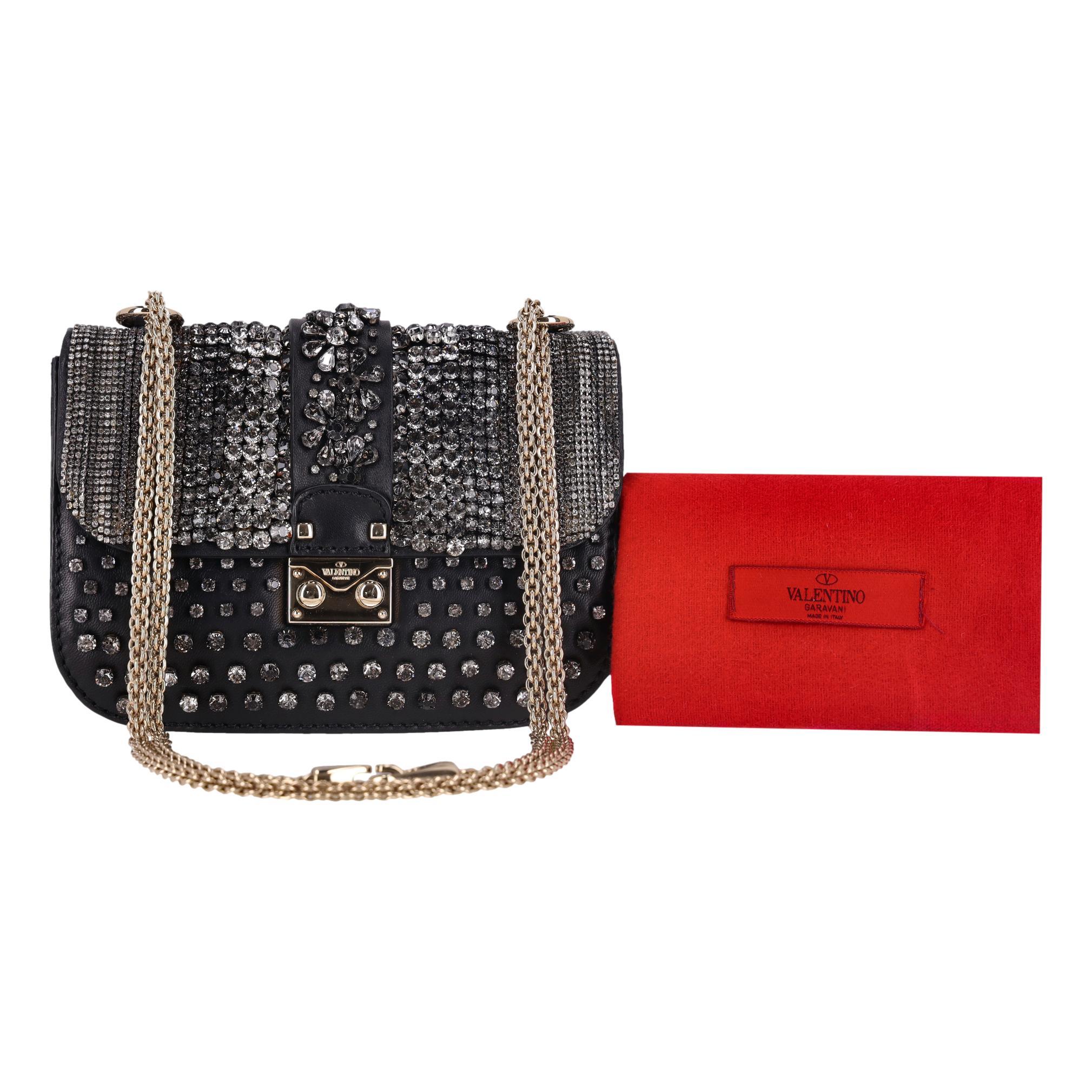 We Adore - Valentino Crystal-Embellished Glam Lock Bag

Sac à bandoulière noir en cuir noir luxueux, orné de cristaux sur toute sa surface.

Le centre du rabat avant est incrusté de motifs en cristal en forme de fleur.

Ferrures dorées, dont la