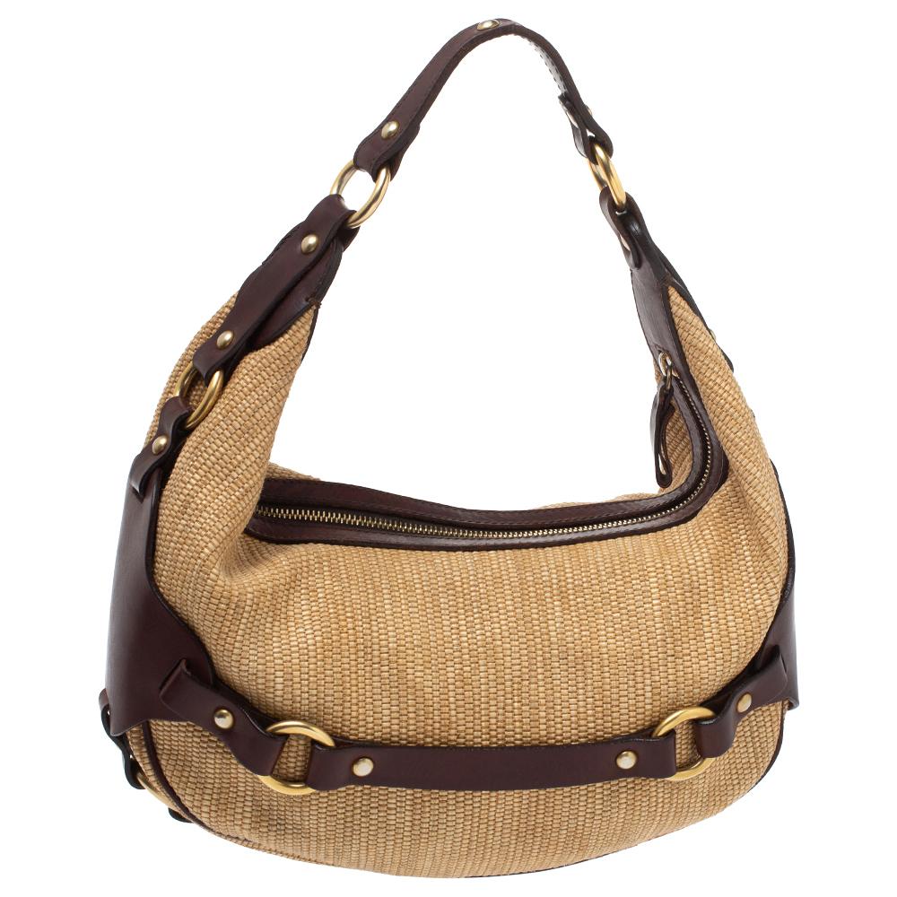 Chic and functional, this hobo from Valentino is a piece you must own! It is crafted from brown and beige raffia and leather and styled with a front strap that carries the signature 'V' logo. Highlighted with gold-tone hardware, it opens to a