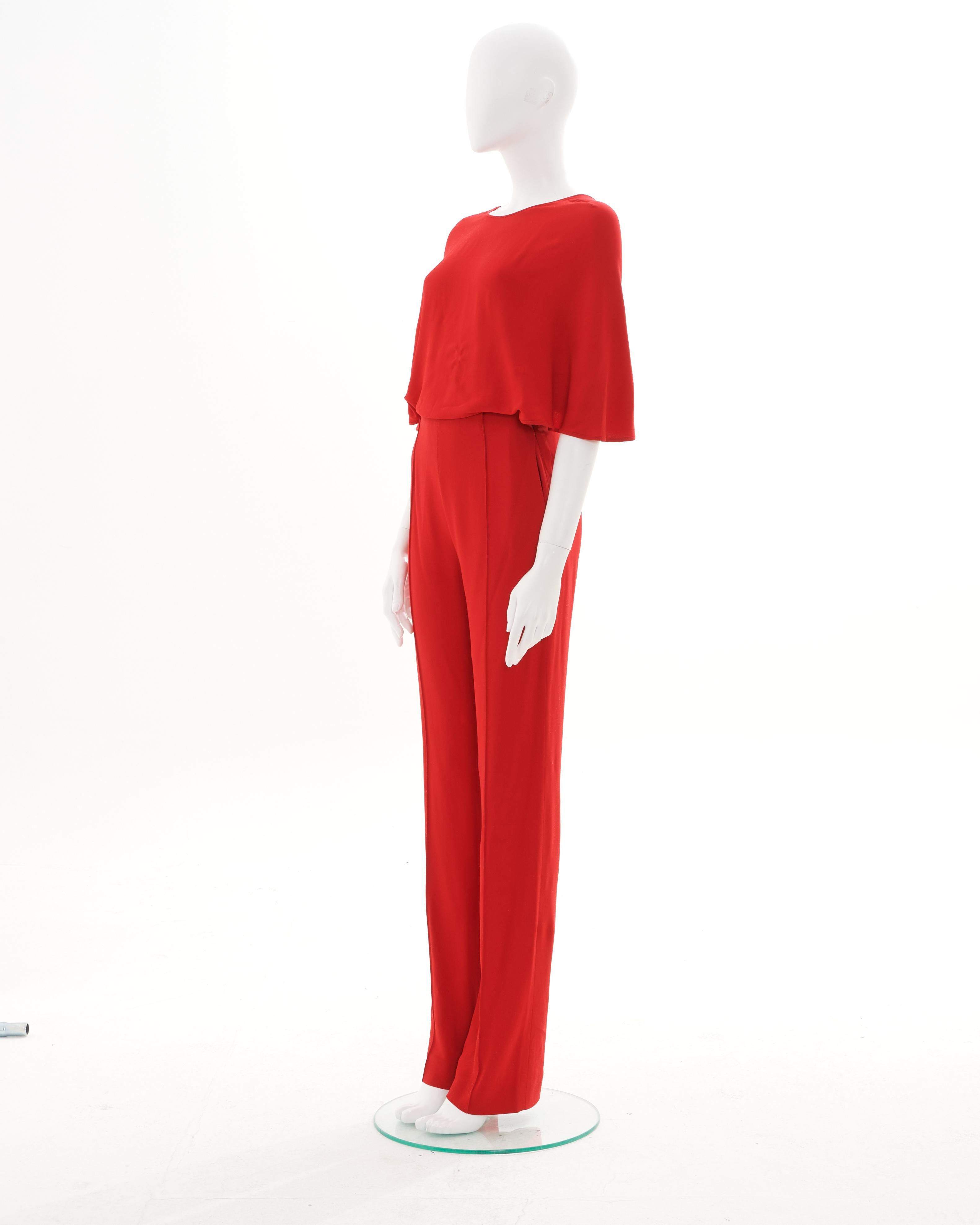 - Conçu par Valentino Garavani
- Vendu par Skof.Archive  
- Début des années 00  
- Combinaison rouge à dos croisé  
- Matériaux : Viscose  
- Silhouette épurée et minimaliste dans un ton rouge audacieux  
- Manches courtes et amples 
- Pantalon de
