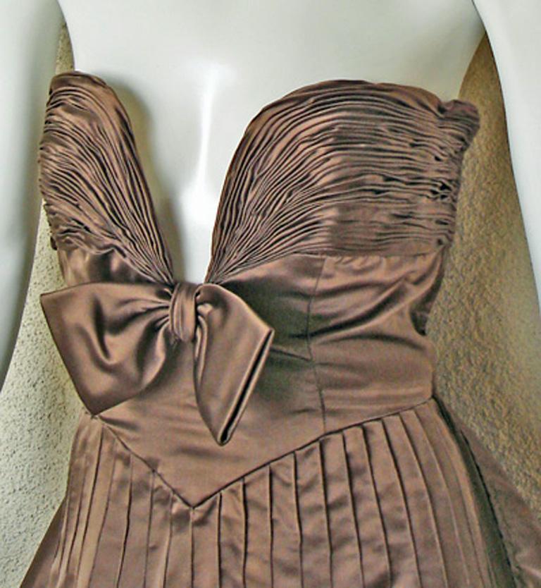 An original Valentino Garavani original runway gown.

Fashioned of rich copper brown duchess satin with plunging fitted bodice accented with hand pleated detail and center bow adornment.  Seath silhouette with long dramatic swantai train.  A