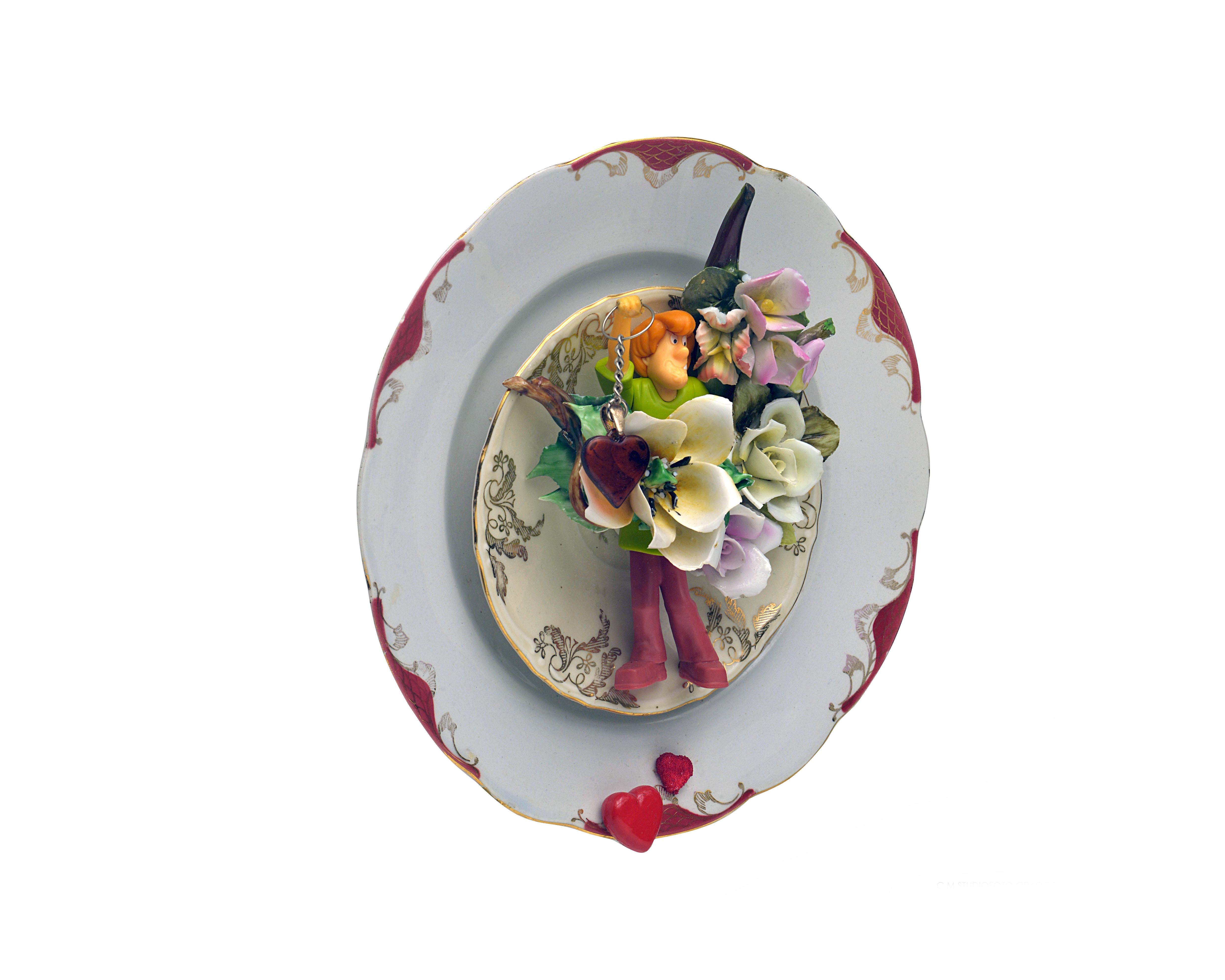 Composición realizada con:
Plato  cerámica.
Fabricación: Anónimo
Plato de té de porcelana con decoración dorada.
Fabricación: Bavaria
Juguetes de plástico y flores de porcelana de Capodimonte.
Sistema de suspensión mediante anilla de metal y