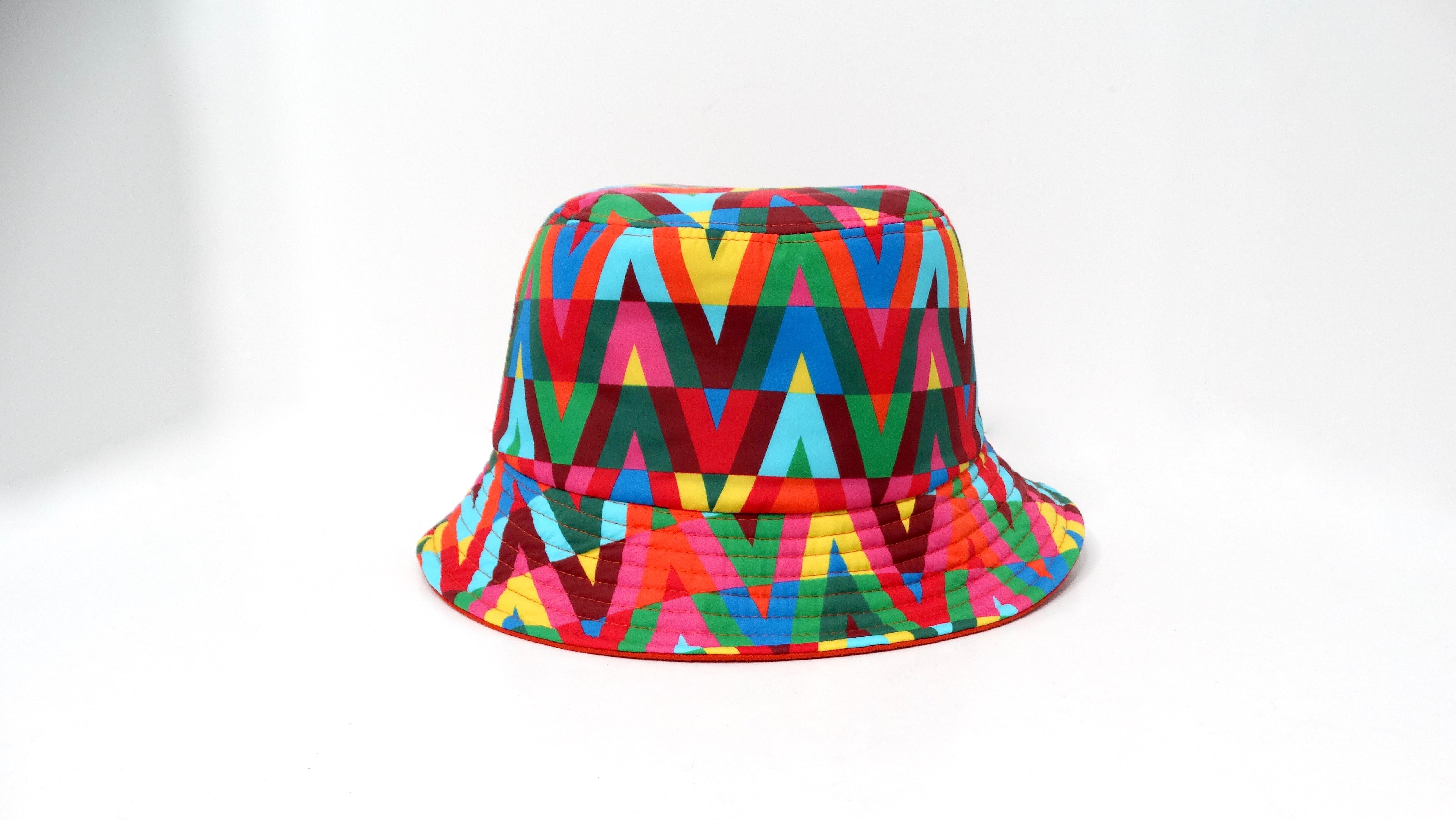 The Valentino Garavani Bright Multicolor V-Print Nylon Bucket Hat is a striking accessory that brings a playful touch to any outfit. Crafted from durable nylon, this hat features the bold, graphic V-print in vibrant colors, making it a statement
