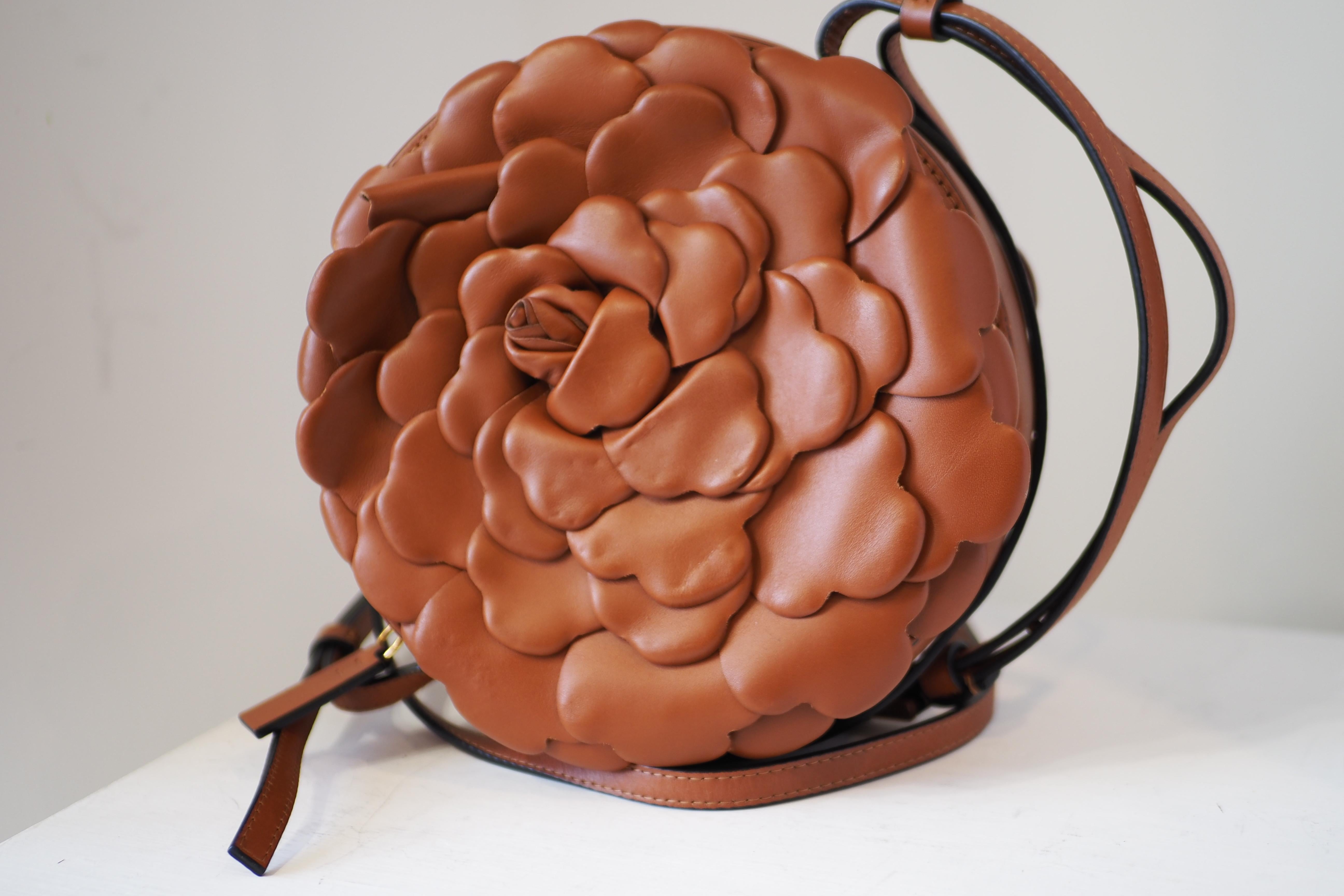 This chic handbag is crafted of brown calfskin leather arranged in a flower motif. This bag features an adjustable shoulder strap with gold hardware. The top zipper opens to a beige canvas interior with card slots.
Base length: 7.25 in

Height: 7.25