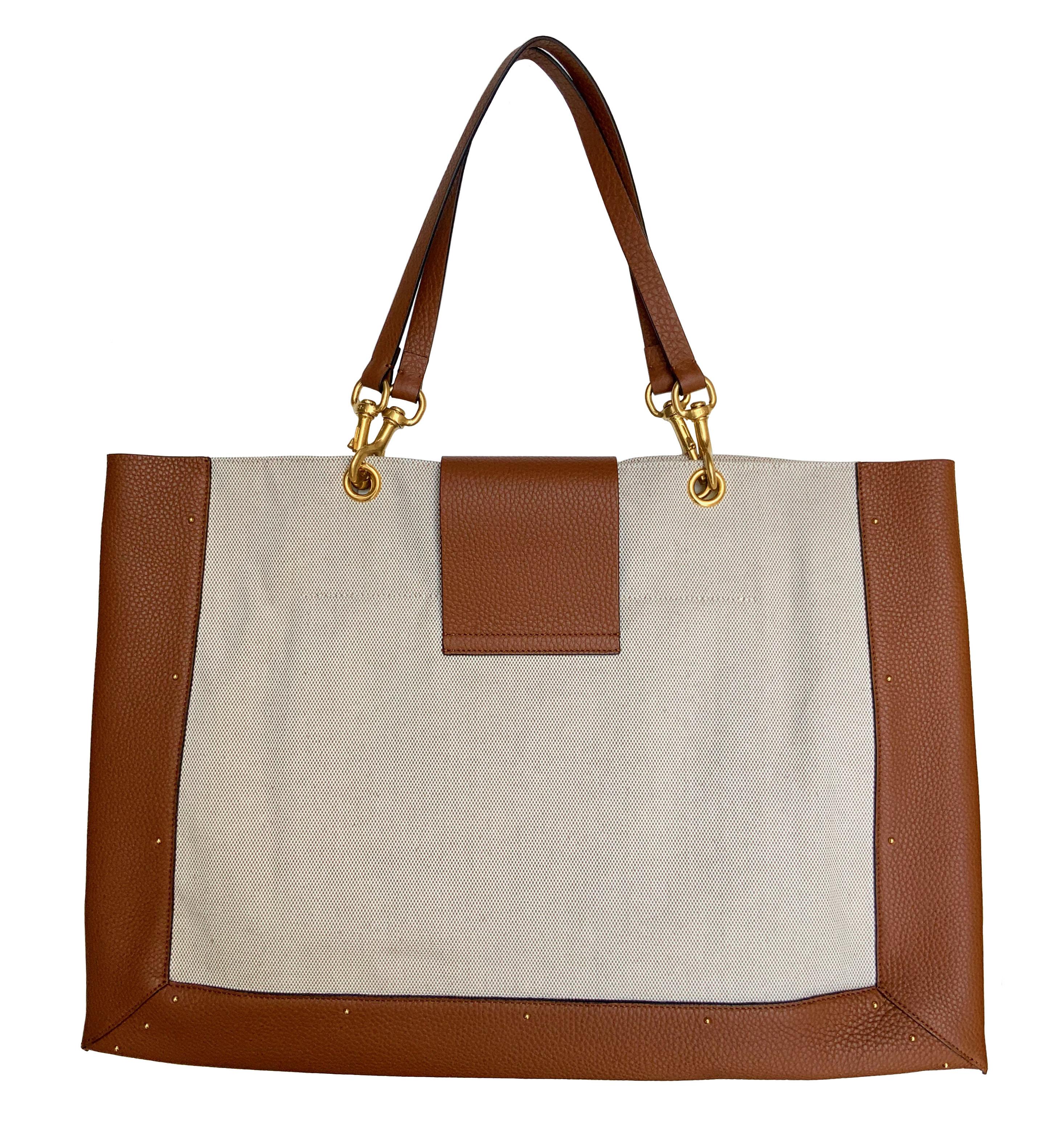 Diese gebrauchte Valentino Tote Bag ist aus beigem Canvas gefertigt und mit hellbraunem Leder besetzt. 
Sie hat eine goldfarbene Logoplakette auf der Vorderseite:: einen Magnetverschluss und eine Innentasche aus rotem Leder mit Reißverschluss.