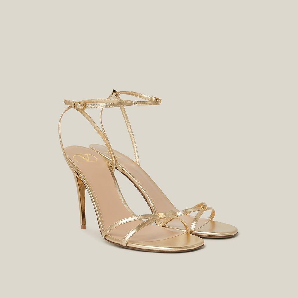 These gold-tone faux leather sandals will elevate any ensemble with Valentino Garavani's signature touch of timeless glamour. They're crafted in Italy from smooth leather with slim, barely-there straps across the toes and ankles and are punctuated