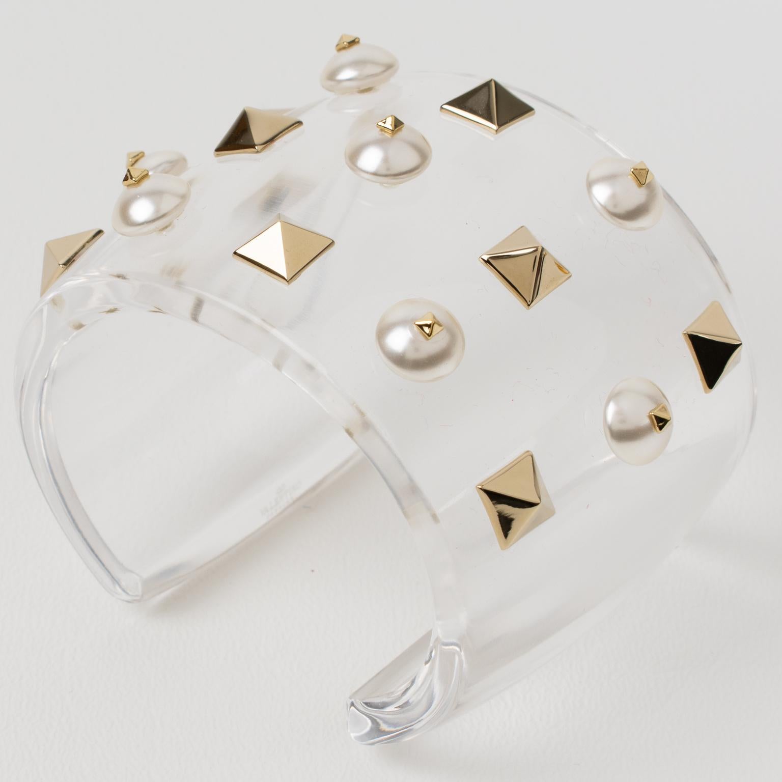 Adorable oversized Valentino Garavani jeweled bracelet bangle. Chunky cuff shape made of crystal clear acrylic resin ornate with chromed metal pyramid studs and topped with pearl-like cabochons. Valentino's hallmark is engraved on the inside of the