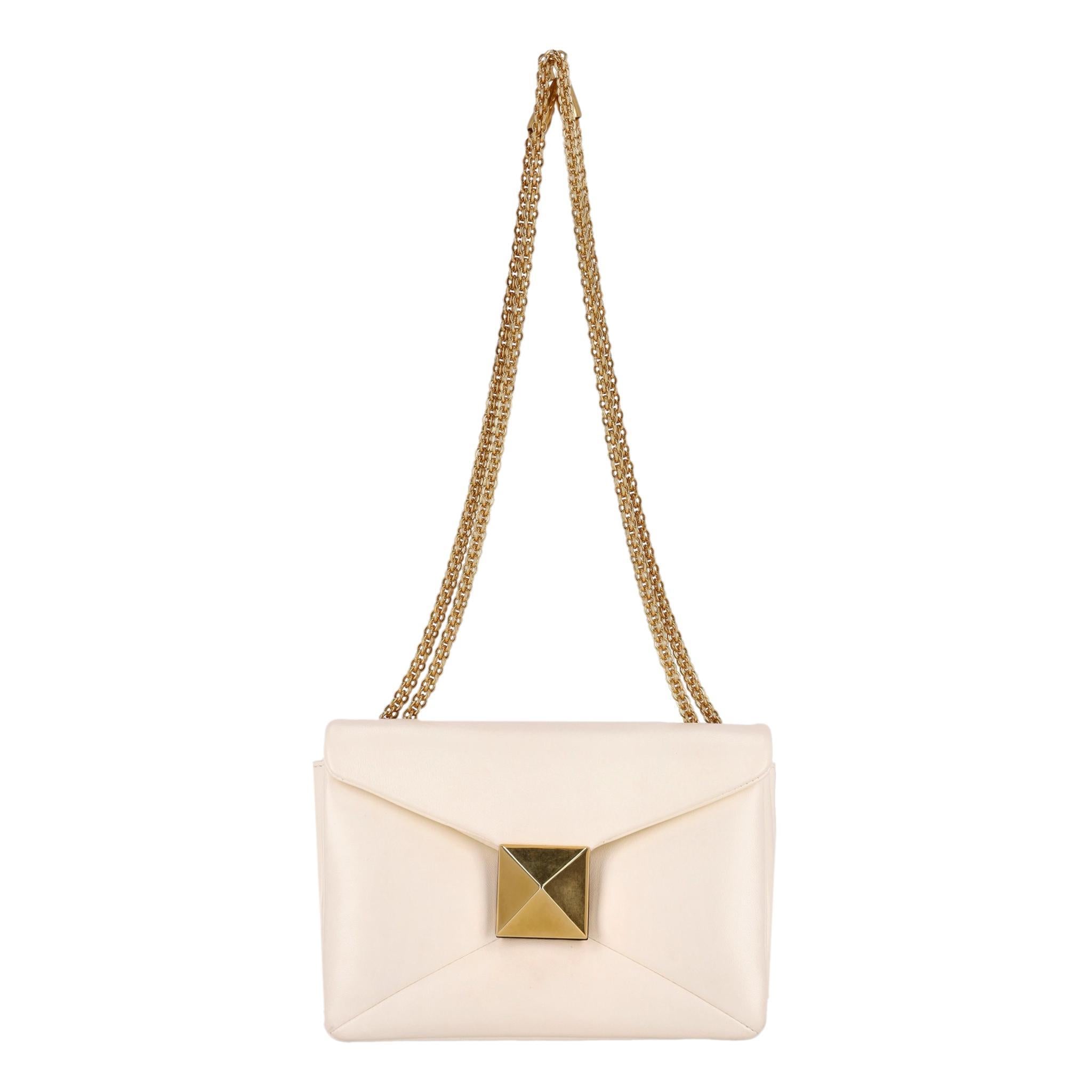 Valentino Garavani - Sac à main en cuir à un clou

 Silhouette enveloppante ivoire/crème et embellissement Rockstud sur le devant, un motif emblématique. Fabriqué en cuir souple. Les ferrures dorées incluent la chaîne qui permet de porter le sac en