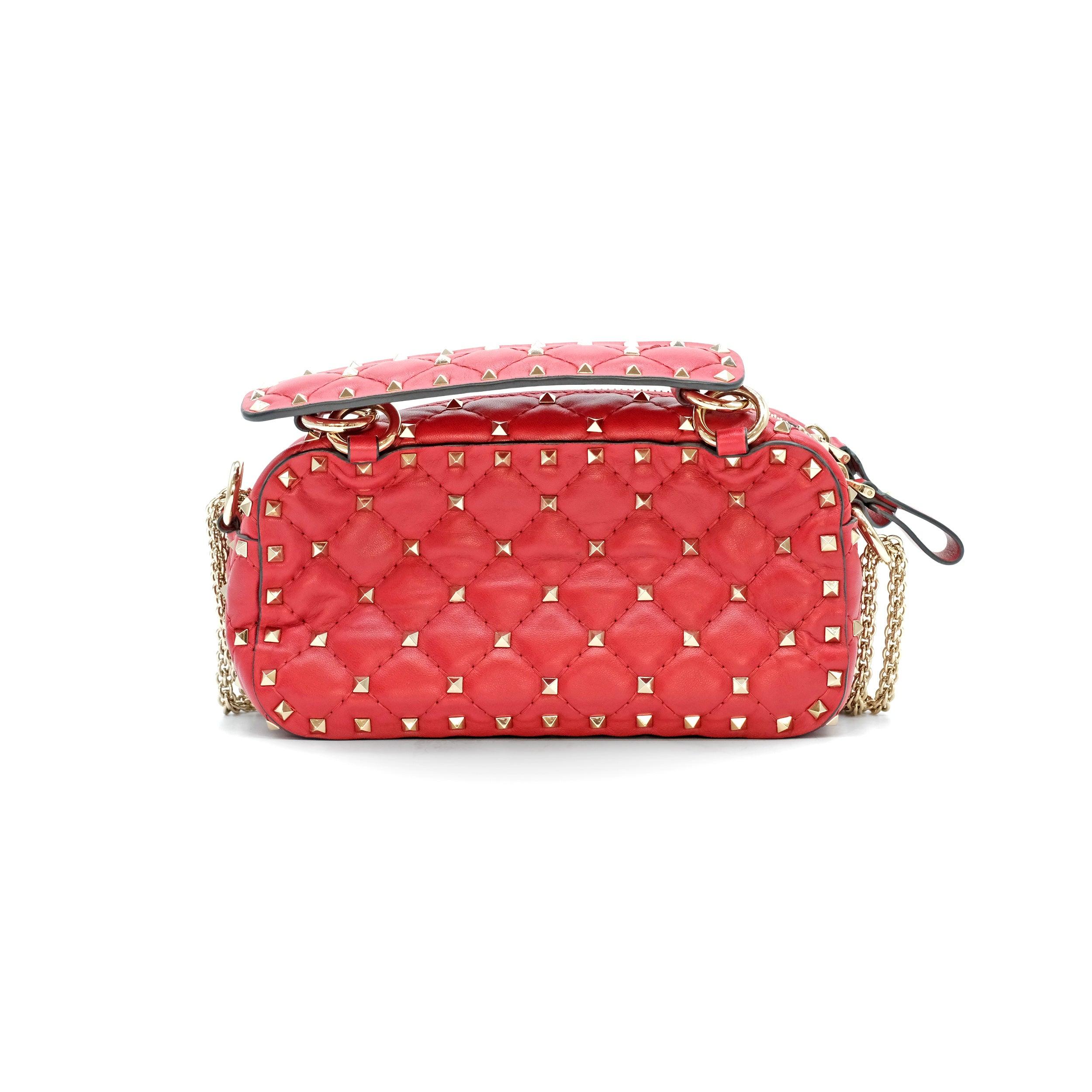 Valentino Garavani Nappa Rockstud Spike Camera Bag in Rosso Valentino. Crafted from luxurious smooth red lambskin leather, this elegant bag features signature gold-tone pyramid studs arranged in a diamond-quilted pattern, adding a bold yet