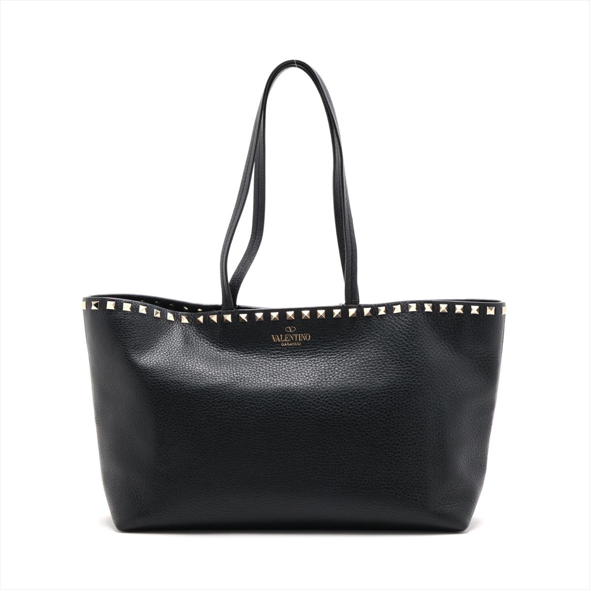 The Valentino Garavani Rockstud Leather Tote Bag in black is an emblem of edgy sophistication. Crafted from smooth leather, its sleek silhouette is accented by silver-tone rockstuds embellishing the upper part, creating a striking contrast against
