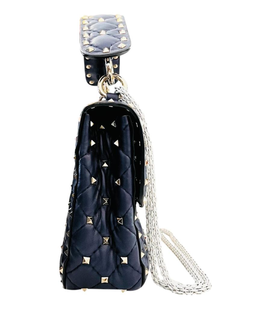 Valentino Garavani Rockstud Spike VLTN Medium Leather Bag
Navy shoulder/crossbody bag crafted in quilted Nappa leather with light gold miniature pyramid shaped Rockstuds.
Detailed with white VLTN print to the front, studded leather top handle and
