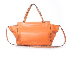Valentino Garavani, Rockstud Trapeze tote in orange.