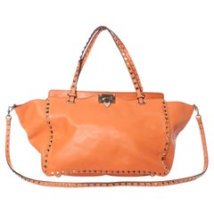 Valentino Garavani, Rockstud Trapeze tote in orange.