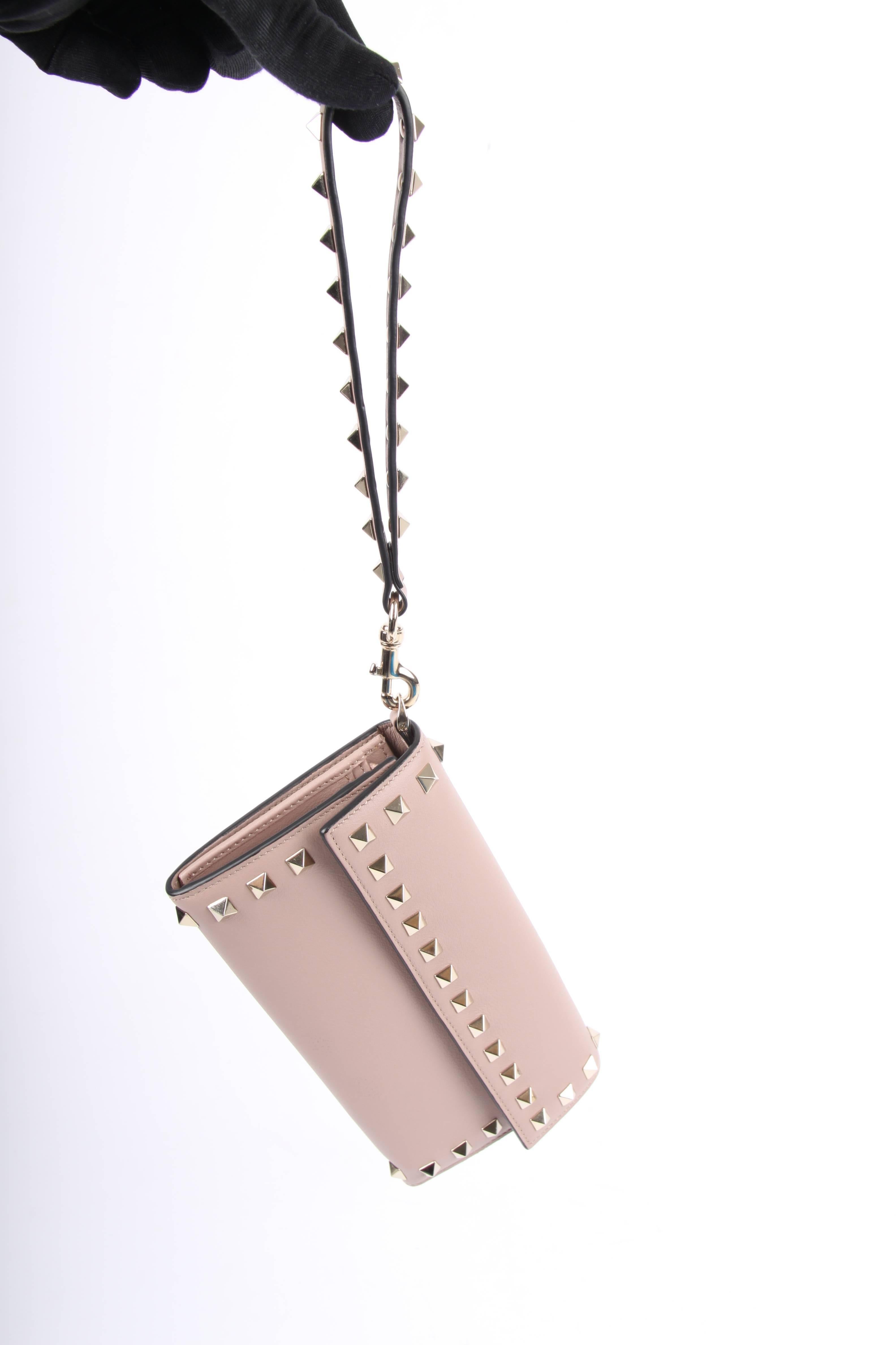 Large wallet by Valentino: this is the Rockstud Wallet. Nice!

Made of leather in a very light shade of taupe with a hint of pink. Of course covered with the welknown square light gold-tone rockstuds. On one side a handy and detachable wrist strap