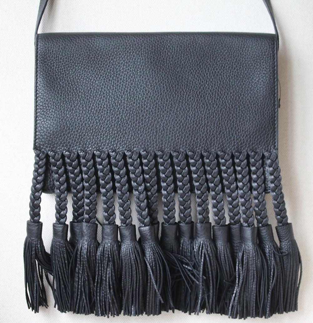 Valentino Garavani pebbled leather shoulder bag with braided fringe trim. Flap top with double snaps. Interior leather lining. One zip pocket. Black leather.  Made in Italy. Does not come with a dustbag or box. 

Dimensions: L 11 x H 7 x D 2