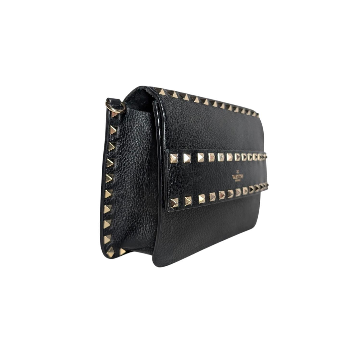 Petit sac crossbody Valentino Garavani Rockstud en cuir de veau grainé, orné de clous et de ferrures en métal platiné. Il est doté d'une poignée frontale cloutée, d'une bandoulière cloutée réglable et amovible, d'une fermeture magnétique et d'une