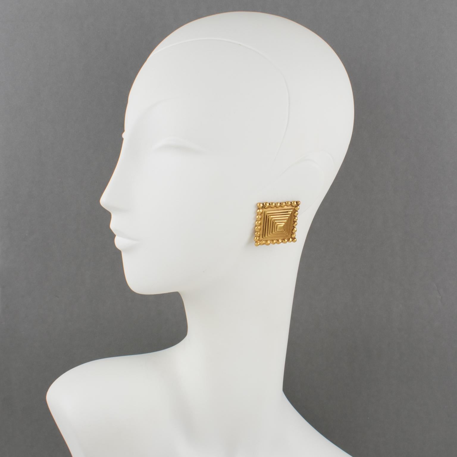 Elegant Valentino Garavani gilt metal clip-on earrings. Dimensional pyramidal shape with brushed gilt metal. Valentino hallmark underside.
Measurements: 1.25 in. wide (3.1 cm) x 1.25 in. high (3.1 cm)
