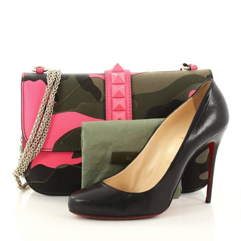 This authentic Valentino Glam Lock Shoulder Bag Camo Leather and Canvas Medium is a fun and bold accessory. Crafted from neon pink and green camo leather and canvas, this beautiful flap bag features a long chain strap, signature pink pyramid studs