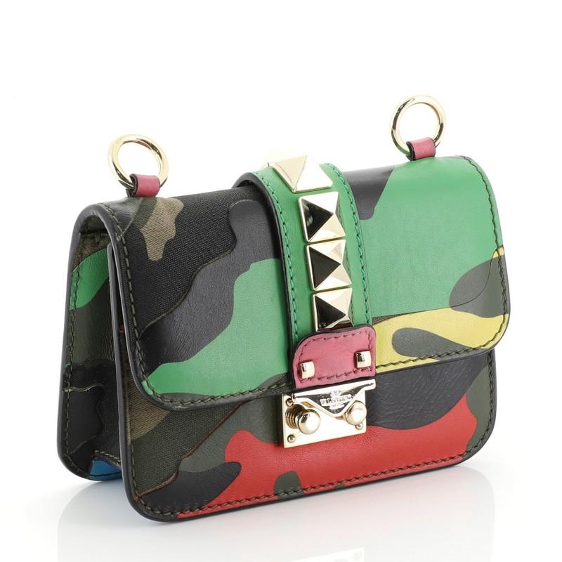 This Valentino Glam Lock Shoulder Bag Camo Leather and Canvas Small, crafted from green, pink and multicolor camo leather and canvas, features a long gold-tone chain strap that allows it to be worn as a crossbody, signature gold pyramid studs at the