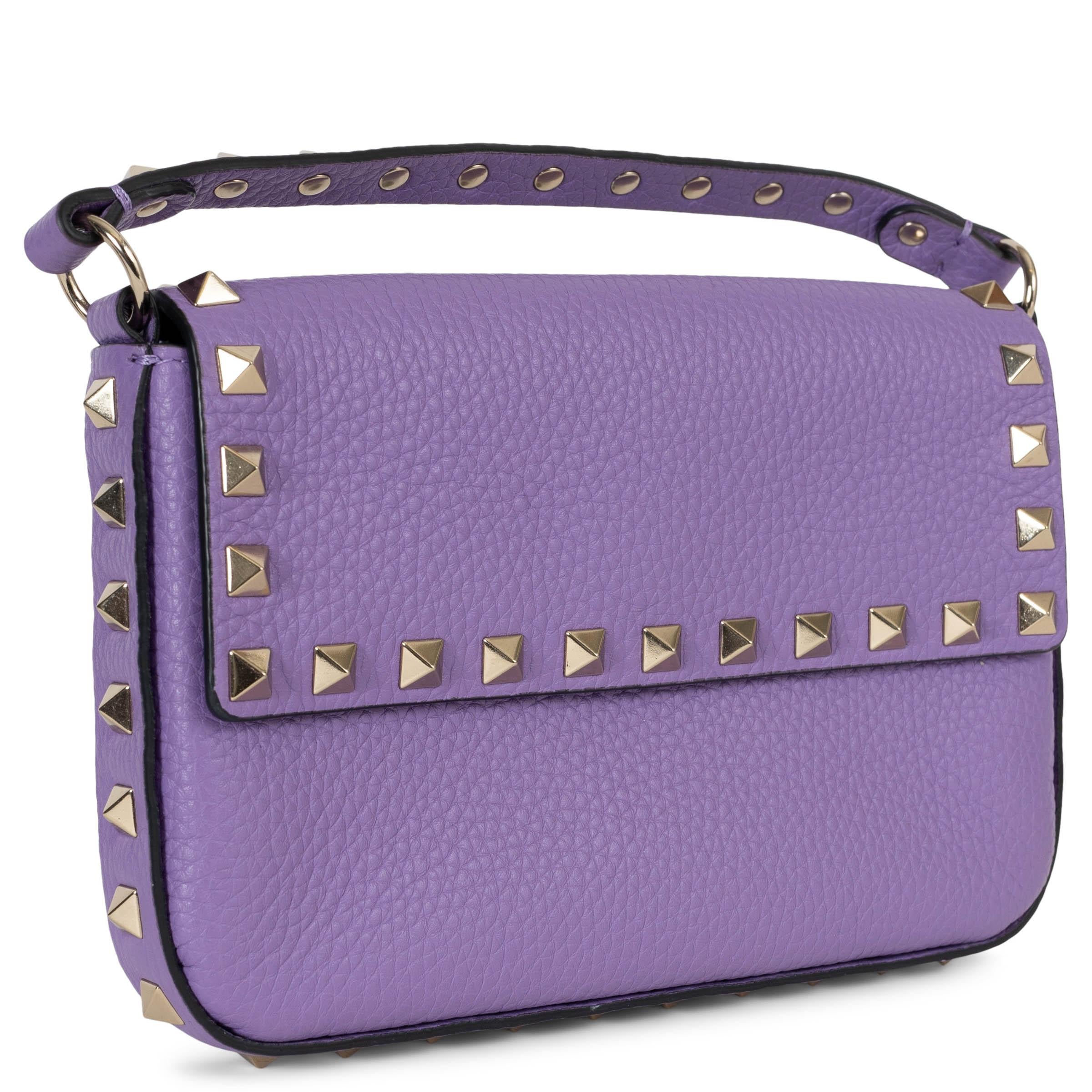 Este bolso bandolera Rockstud Pouch 100% auténtico de Valentino en piel de becerro granulada de color Glicine (morado claro) es una pieza con estilo. Adornada con las emblemáticas tachuelas piramidales platinadas a lo largo de los bordes y los