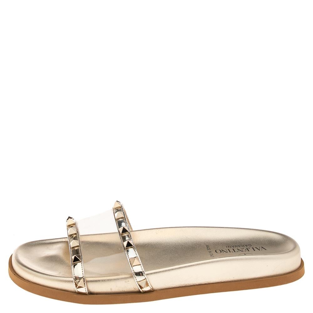 Comfort and style come together with these slide sandals from Valentino! The gold slides are crafted from leather and feature an open-toe silhouette. They flaunt a PVC panel and Rockstud accents on the ​vamp straps and are sure to make your feet