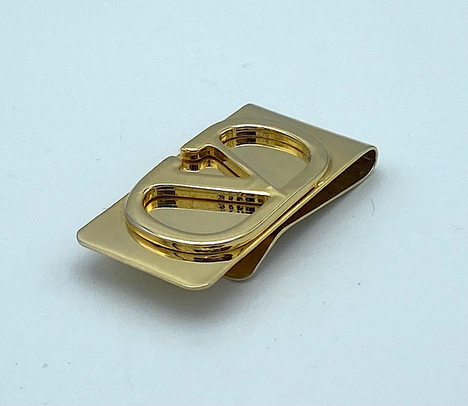 A 1980s gold plate money clip from house of Valentino in Italy. It is 1 inch wide and 2 inches long with a large Valentino logo of a 