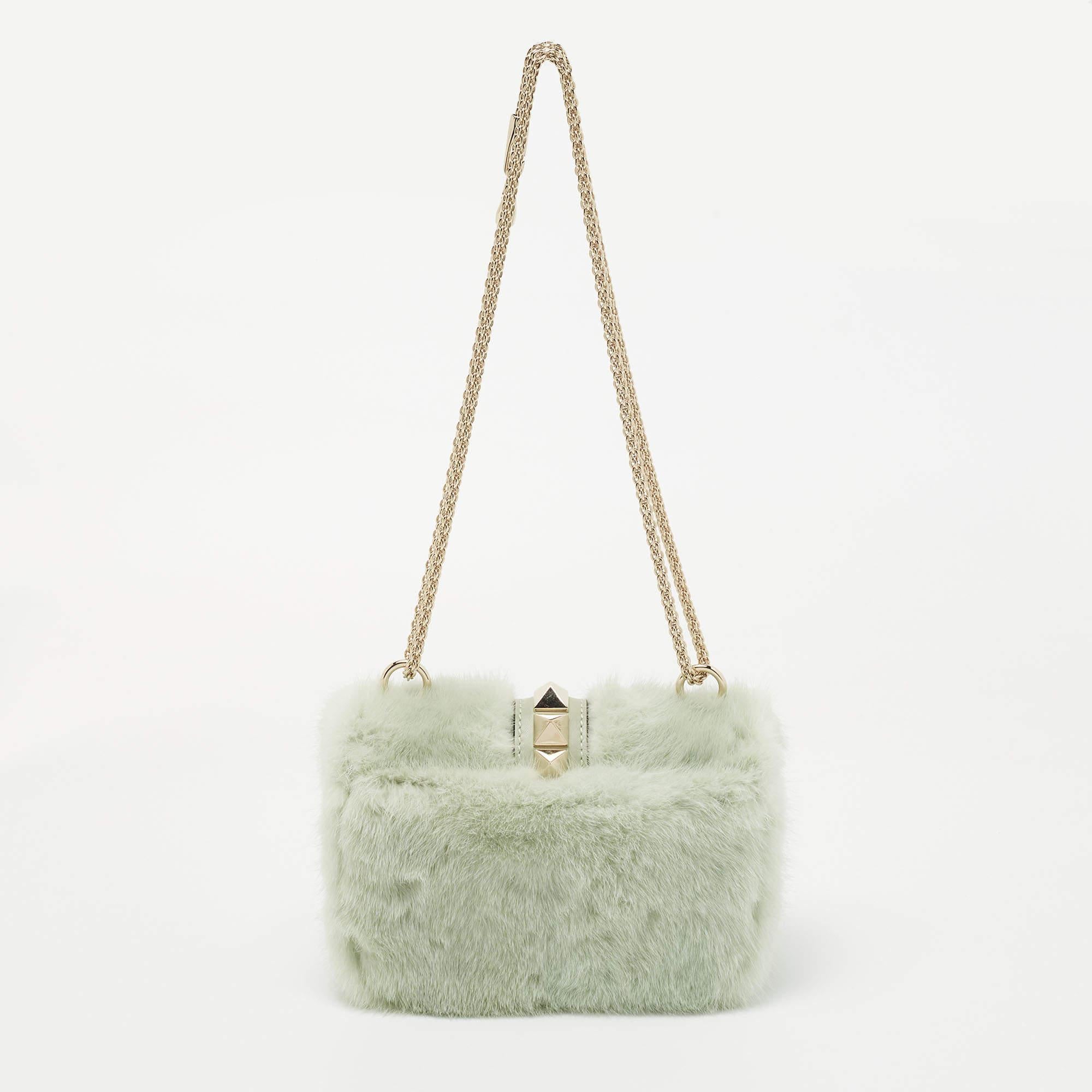 Celebrating the rich heritage of the brand, this Valentino bag is decorated with Rockstuds. It is made from fur and it showcases a noteworthy design. Lined with leather, it is secured by a branded lock closure on the front flap. While the chain