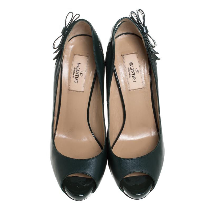 Work your magic while donning this pair of pumps from the iconic house of Valentino. Crafted in Italy, they are made from leather and patent leather. These green pumps are styled with peep toes, 12 cm heels, platforms and bow detailing near the
