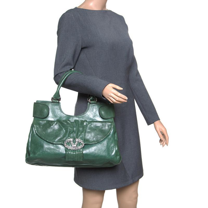 This lush green shoulder bag from Valentino radiates a charm that will amaze the crowds wherever you go! The bag is crafted from leather and features an artistuic silhouette. It flaunts dual top handles, a front flap closure with a crystal